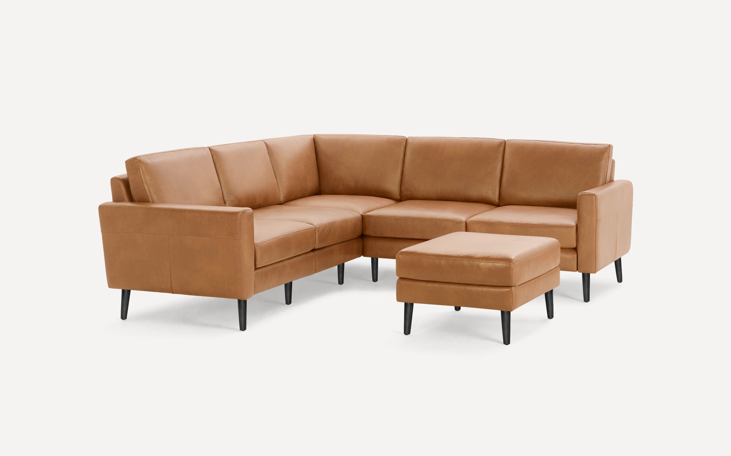 Modern L-shaped sectional sofa in tan leather with black tapered legs and a matching square ottoman, set against a white background.