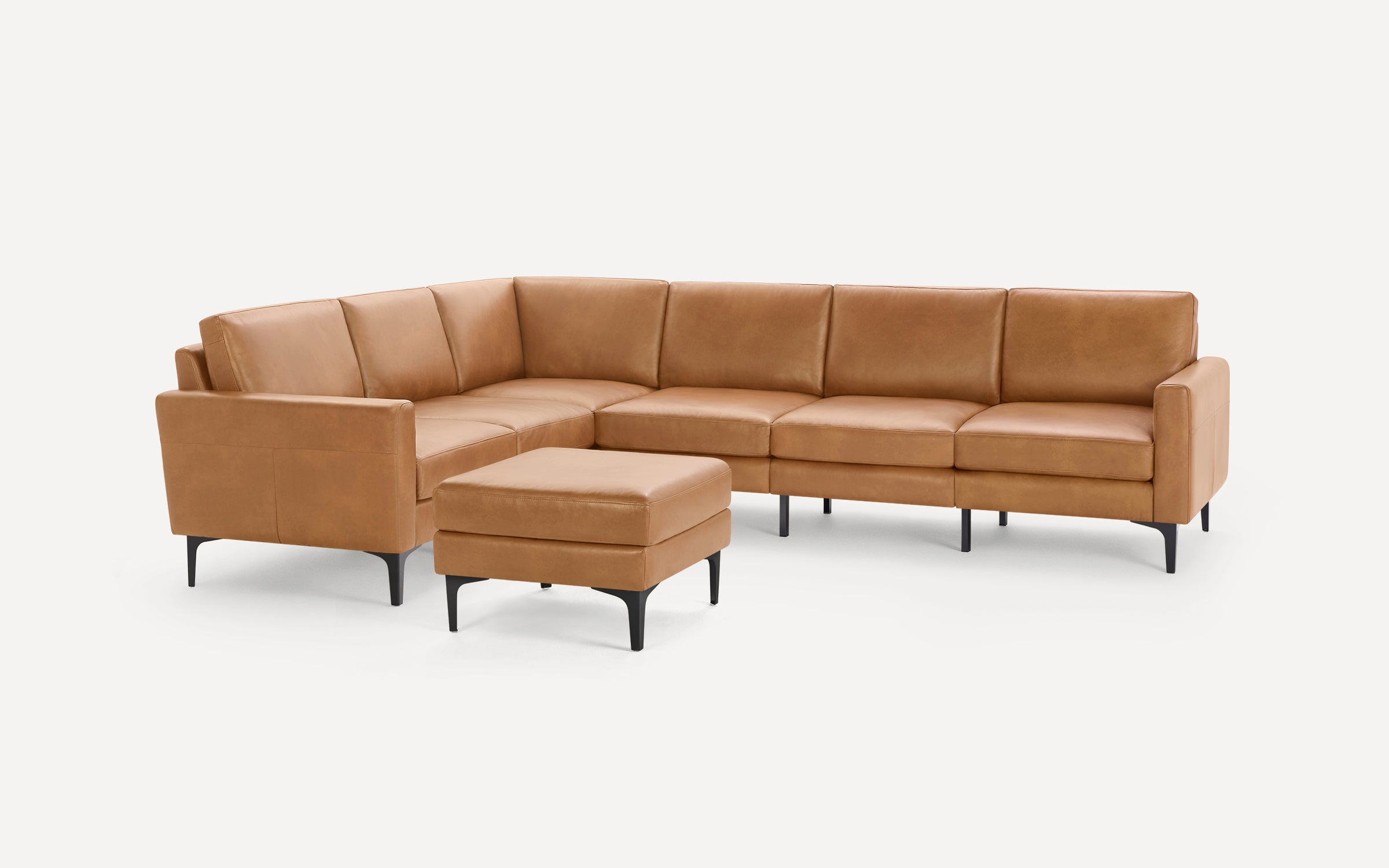 Modern tan leather sectional sofa with clean lines, black metal legs, and matching ottoman on plain white background.