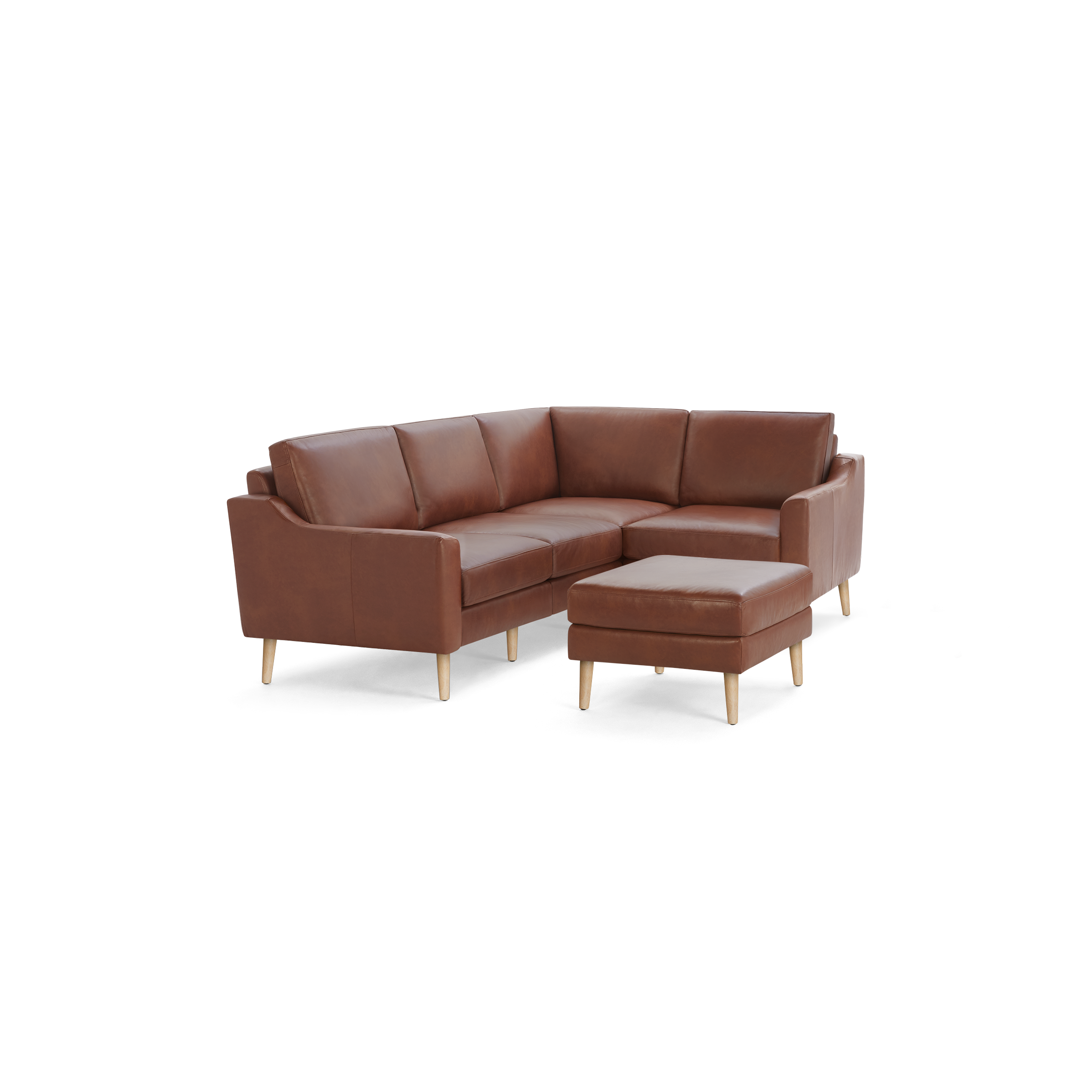 Brown leather L-shaped sectional sofa with wooden legs, accompanied by a matching ottoman on a black background.