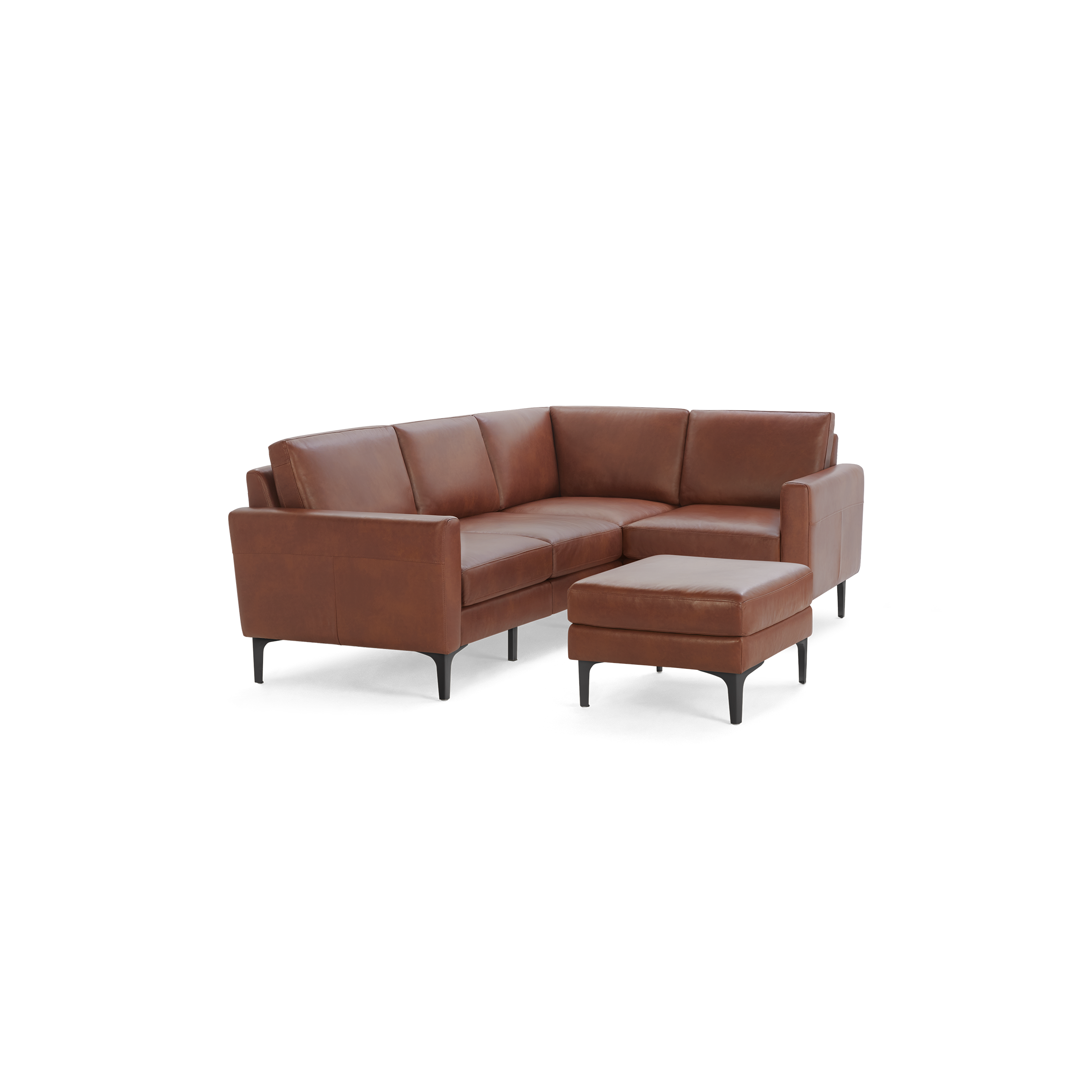 Modern L-shaped sectional sofa in warm brown leather with slim black legs and matching ottoman on black background.