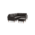 Dark gray leather L-shaped sectional sofa with wooden legs and matching ottoman against black background.
