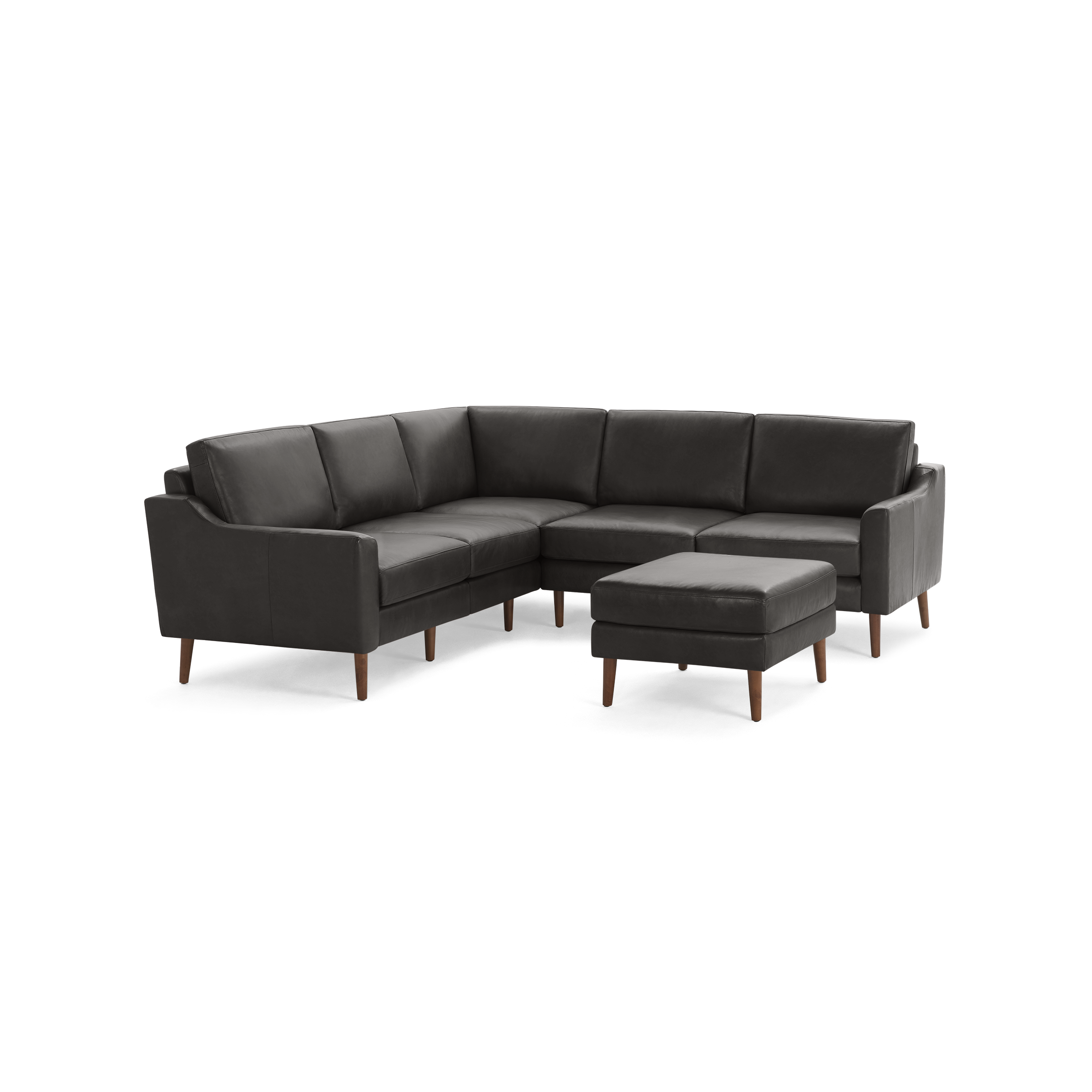 Modern dark gray L-shaped sectional sofa with wooden legs and matching square ottoman isolated on black background.