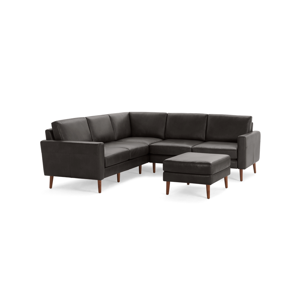 Dark gray L-shaped sectional sofa with wooden legs and matching ottoman, featuring clean lines and modern design.
