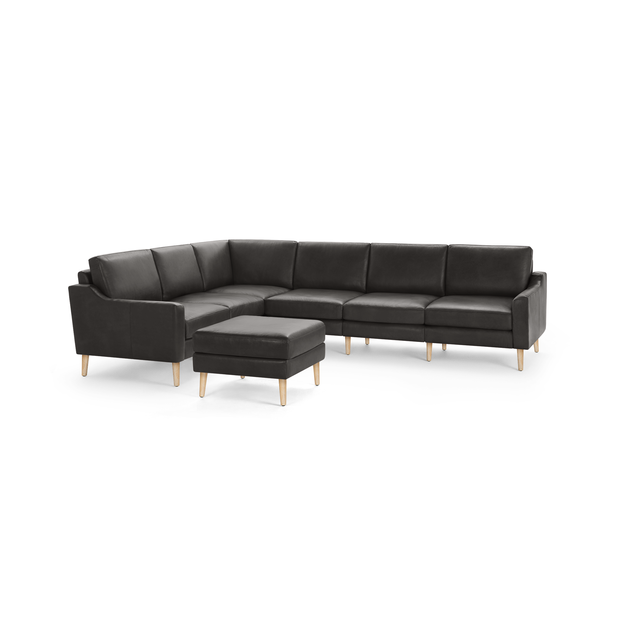 Dark gray leather sectional sofa with wooden legs and matching ottoman, modern and minimalist design.
