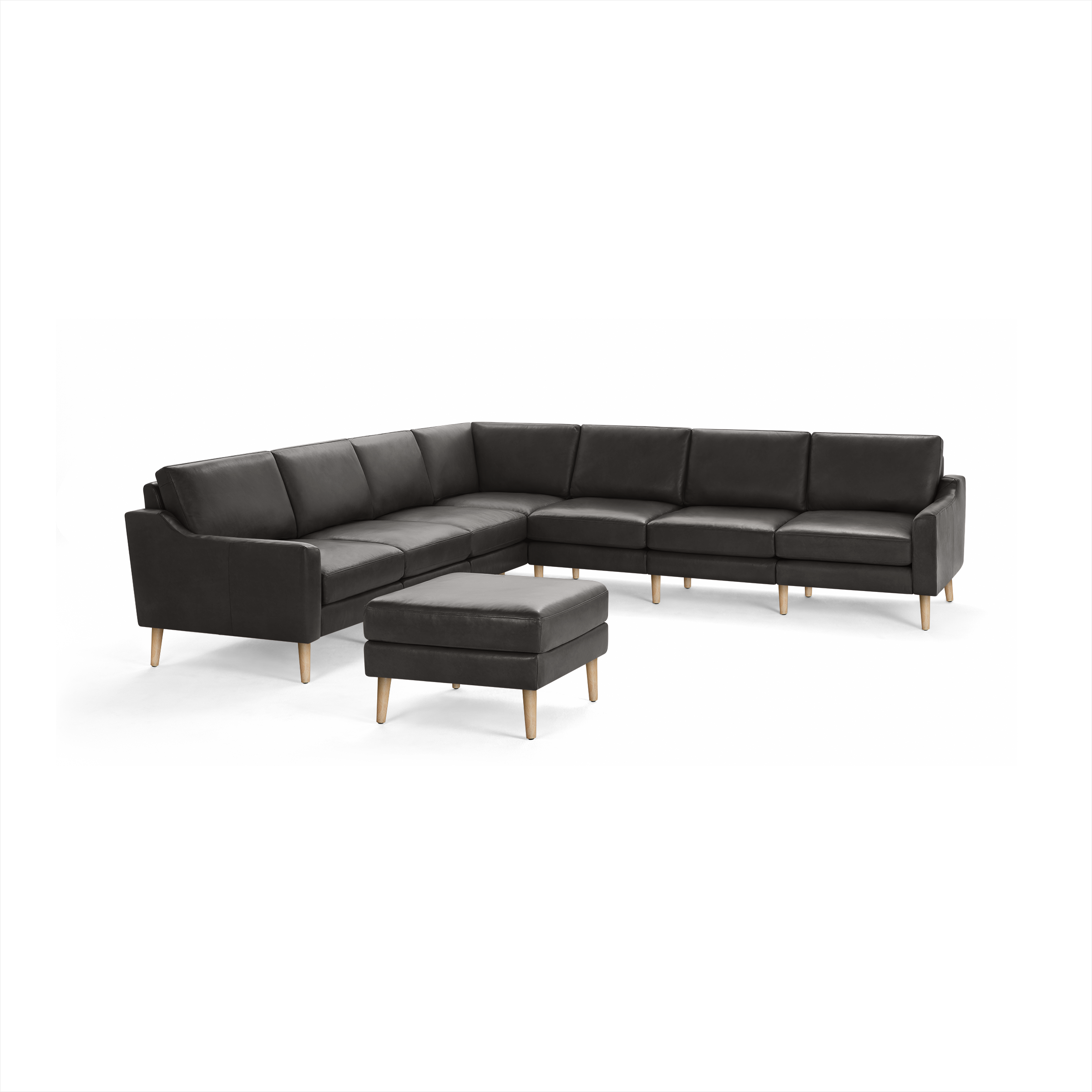 Dark gray leather L-shaped sectional sofa with wooden legs, paired with matching ottoman, minimalist modern design.