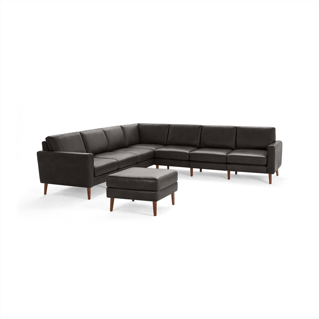 Dark grey leather sectional sofa with wooden legs and matching ottoman, modern L-shaped design.