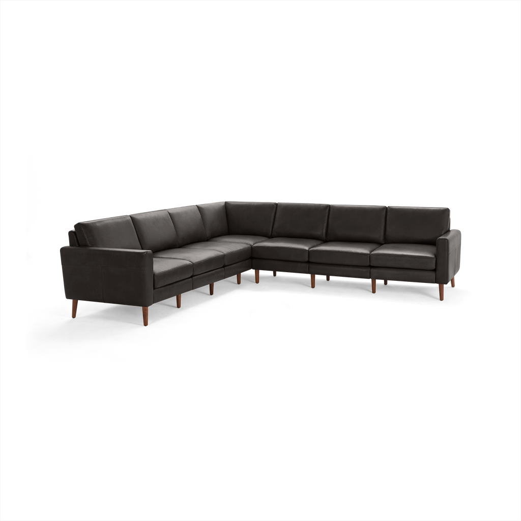 Large black leather sectional sofa with wooden legs, featuring a modern design and cushioned seats and backrests.