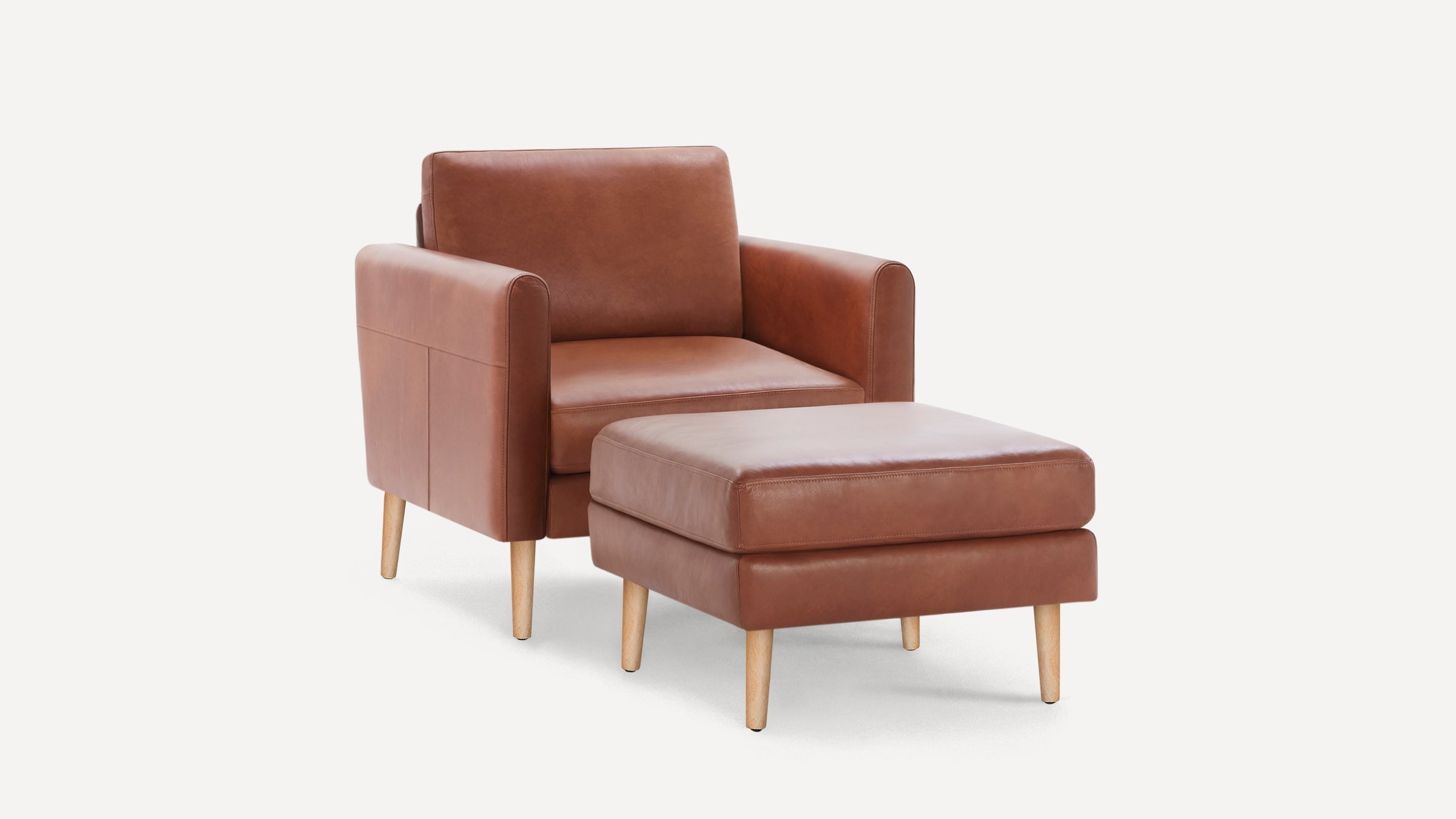 Brown leather armchair with matching ottoman, featuring wooden legs and clean, modern design on a white background.