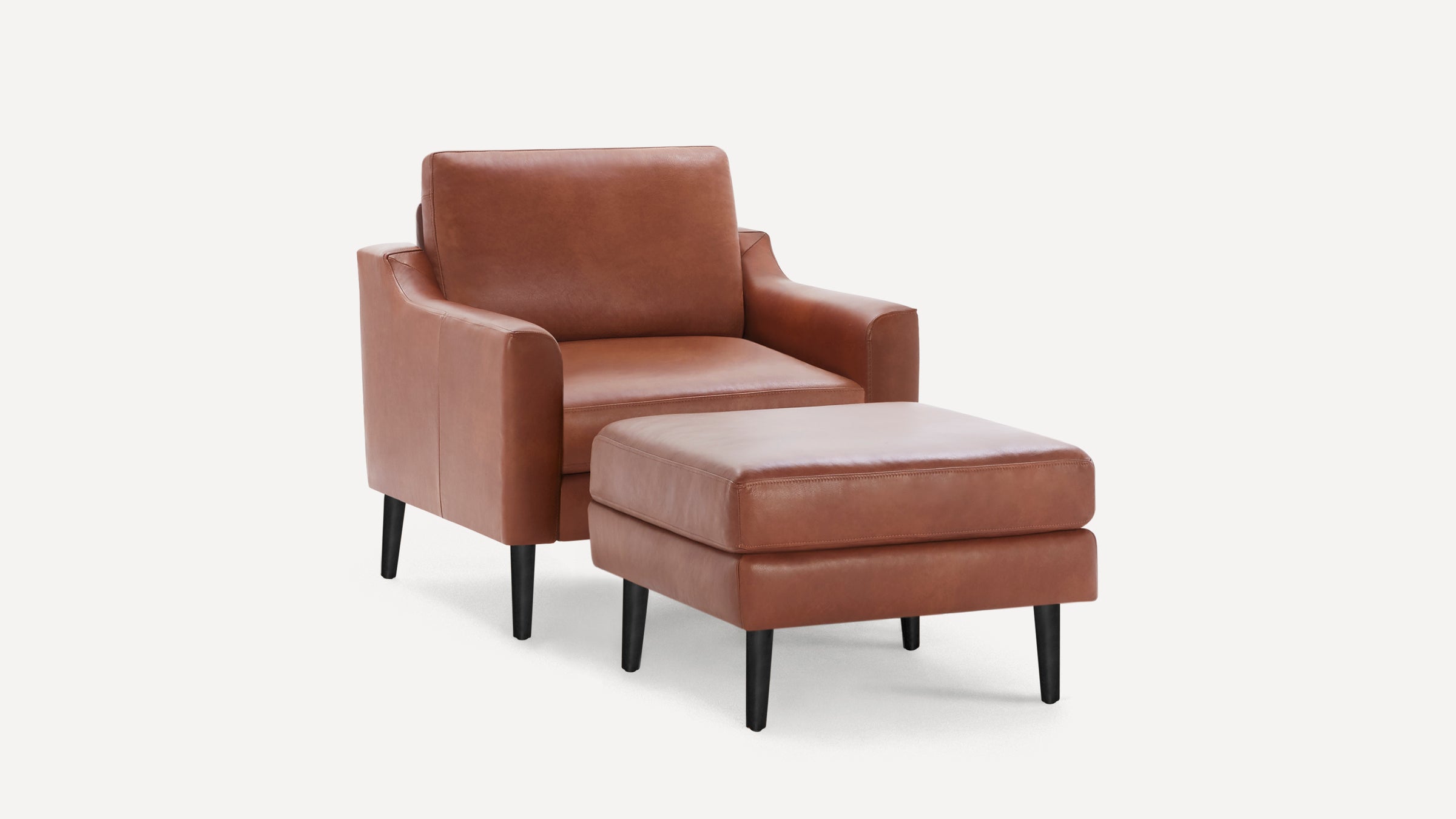 Modern brown leather armchair with matching ottoman, both featuring black tapered wooden legs and smooth cushion design.