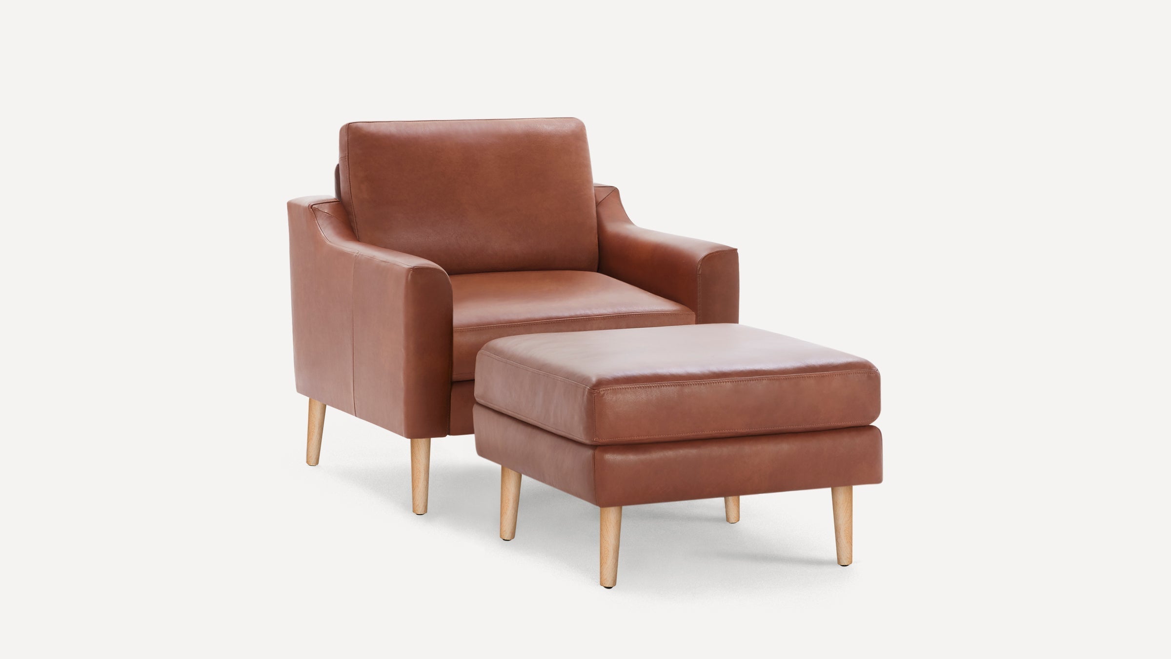 Brown leather armchair with matching ottoman, both featuring light wooden legs, set against a white background.