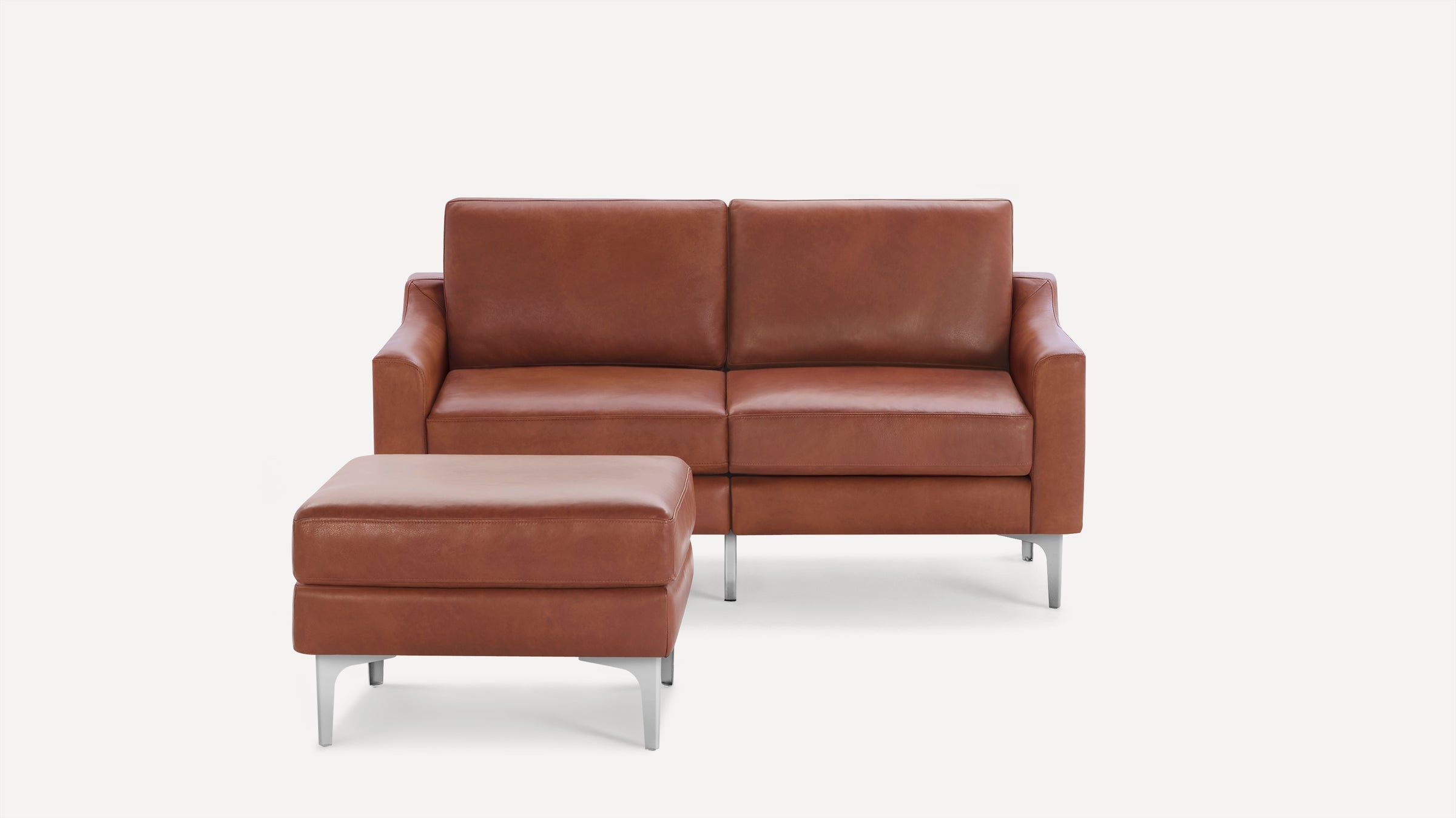 Modern brown leather two-seater sofa with matching ottoman, supported by sleek silver metal legs on a white background.