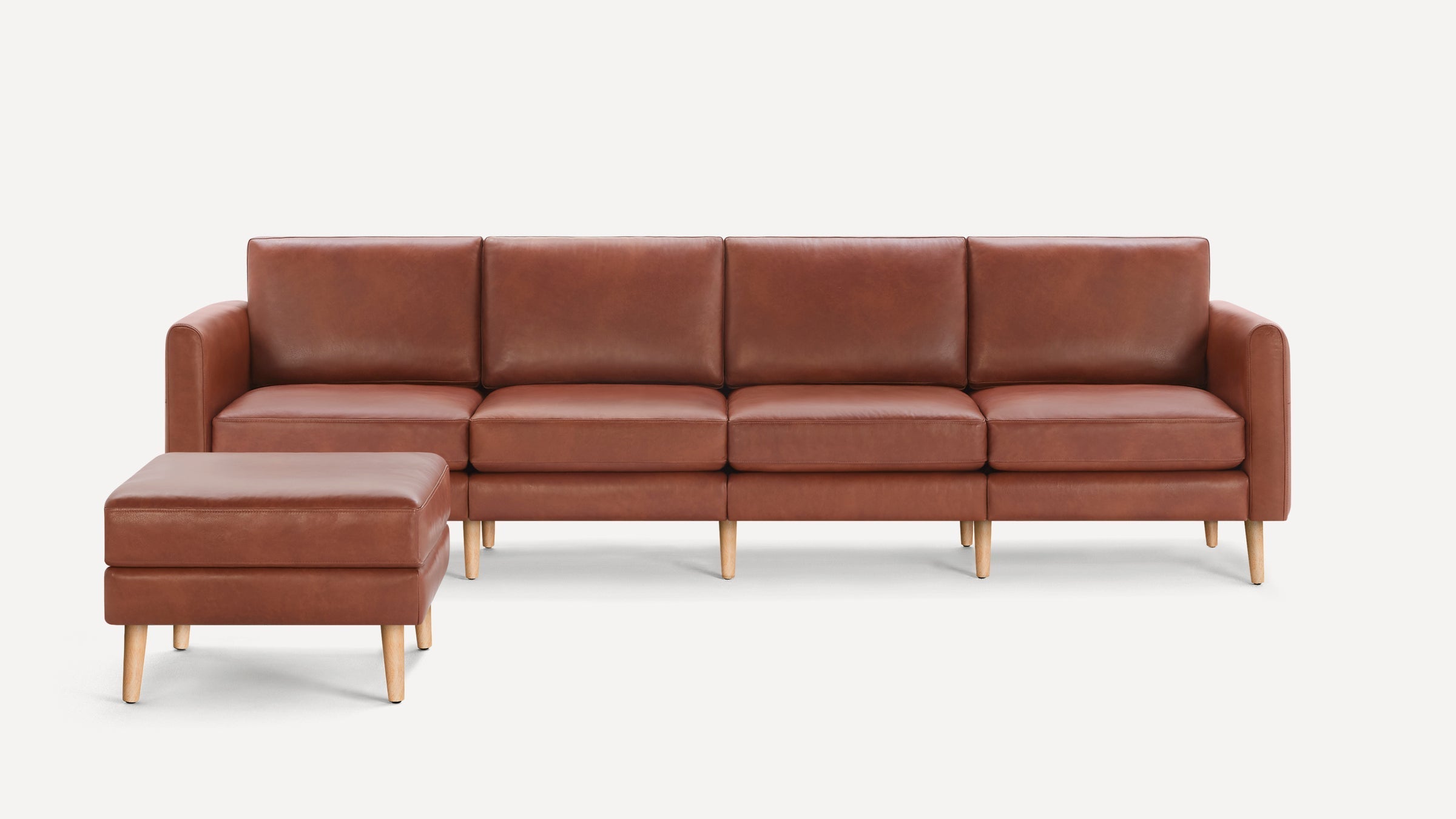 Modern brown leather sectional sofa with matching ottoman, featuring clean lines and light wooden legs on a white background.