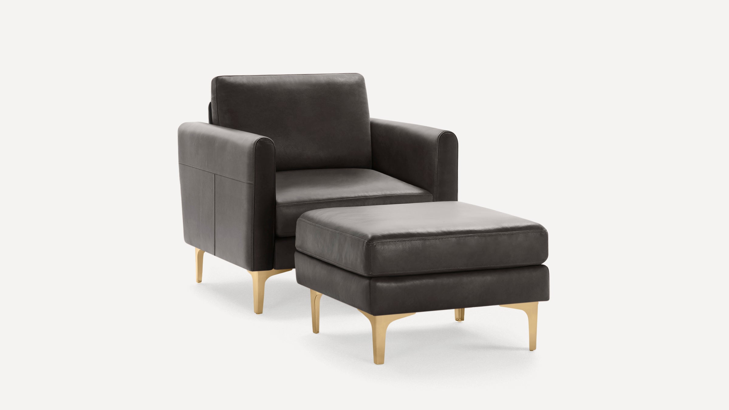 Dark gray leather armchair with matching ottoman, both featuring sleek golden metal legs.