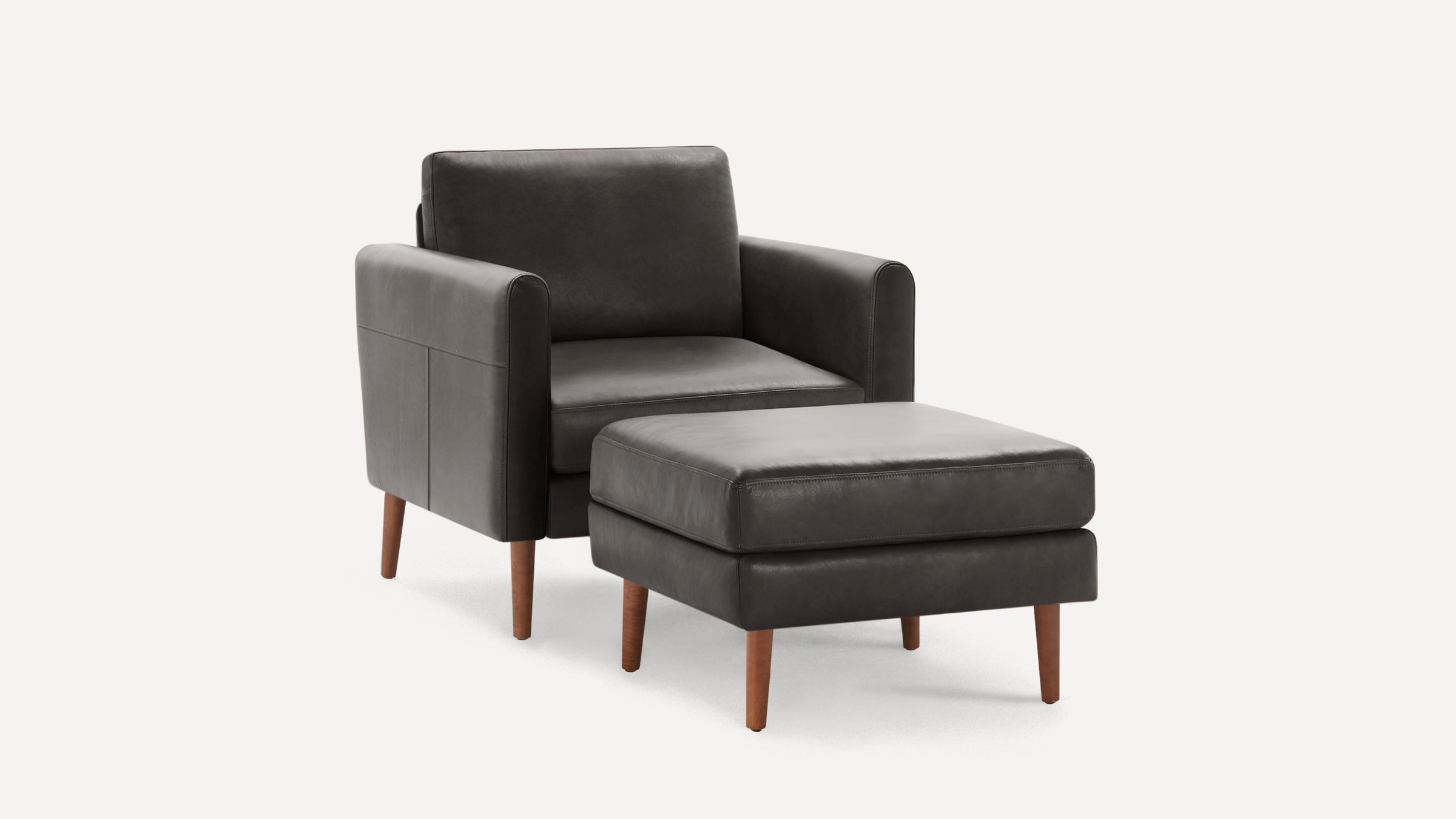 Dark gray leather armchair with matching ottoman, both featuring wooden tapered legs and clean modern design.