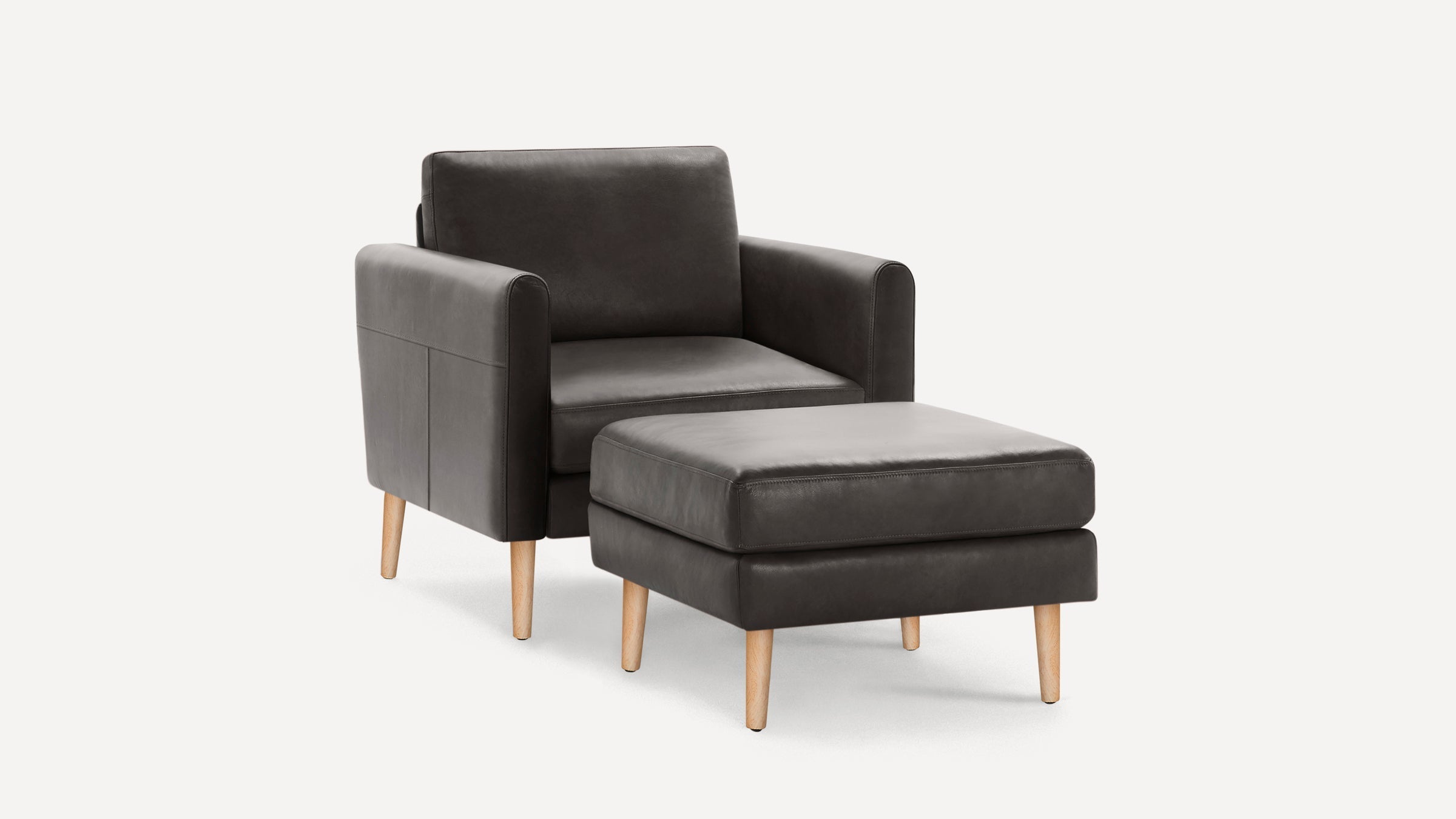 Dark gray leather armchair with matching ottoman, both featuring light wooden legs and a modern, minimalist design.