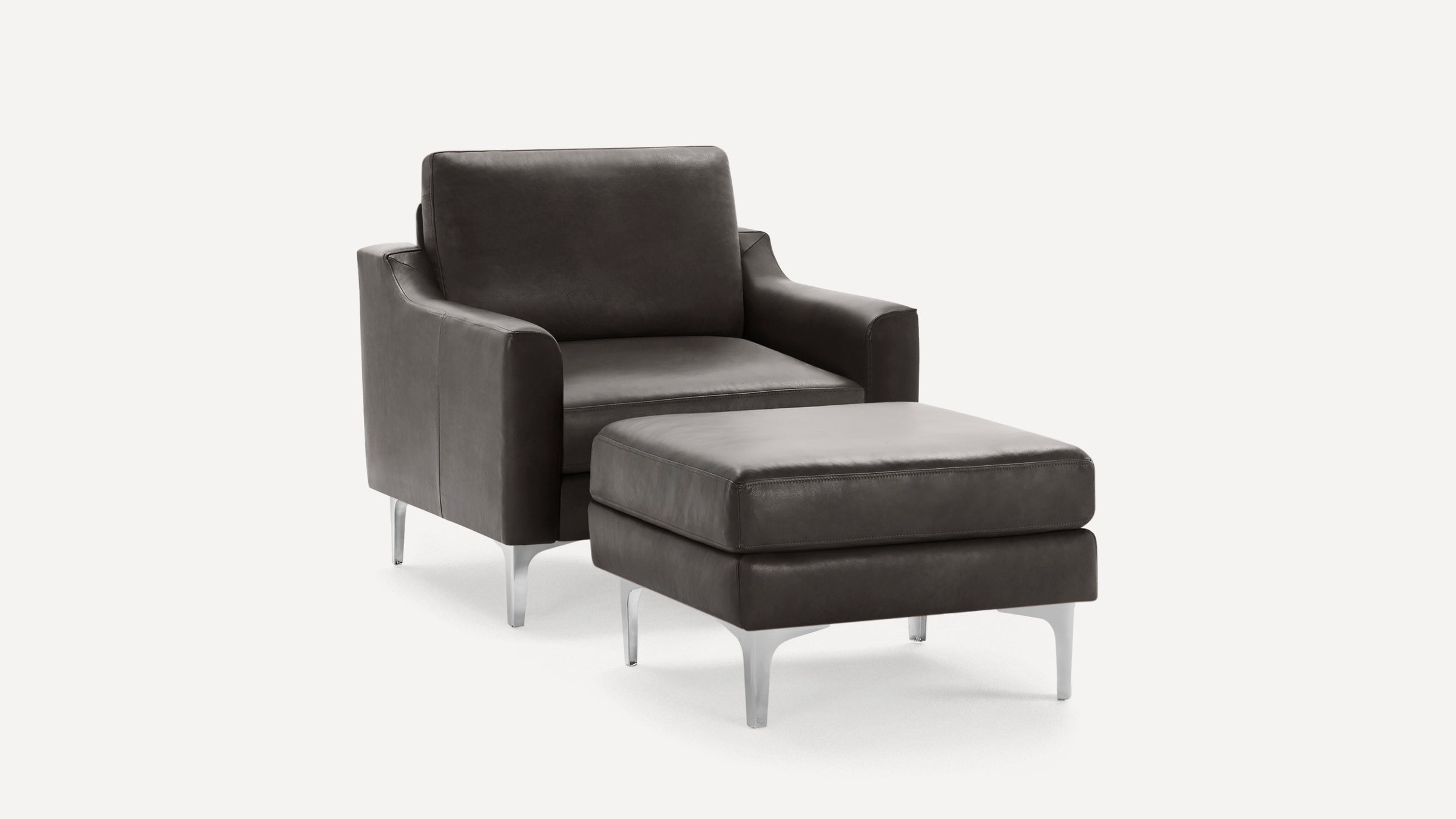 Dark gray leather armchair with matching ottoman, featuring sleek metal legs and modern, clean lines.
