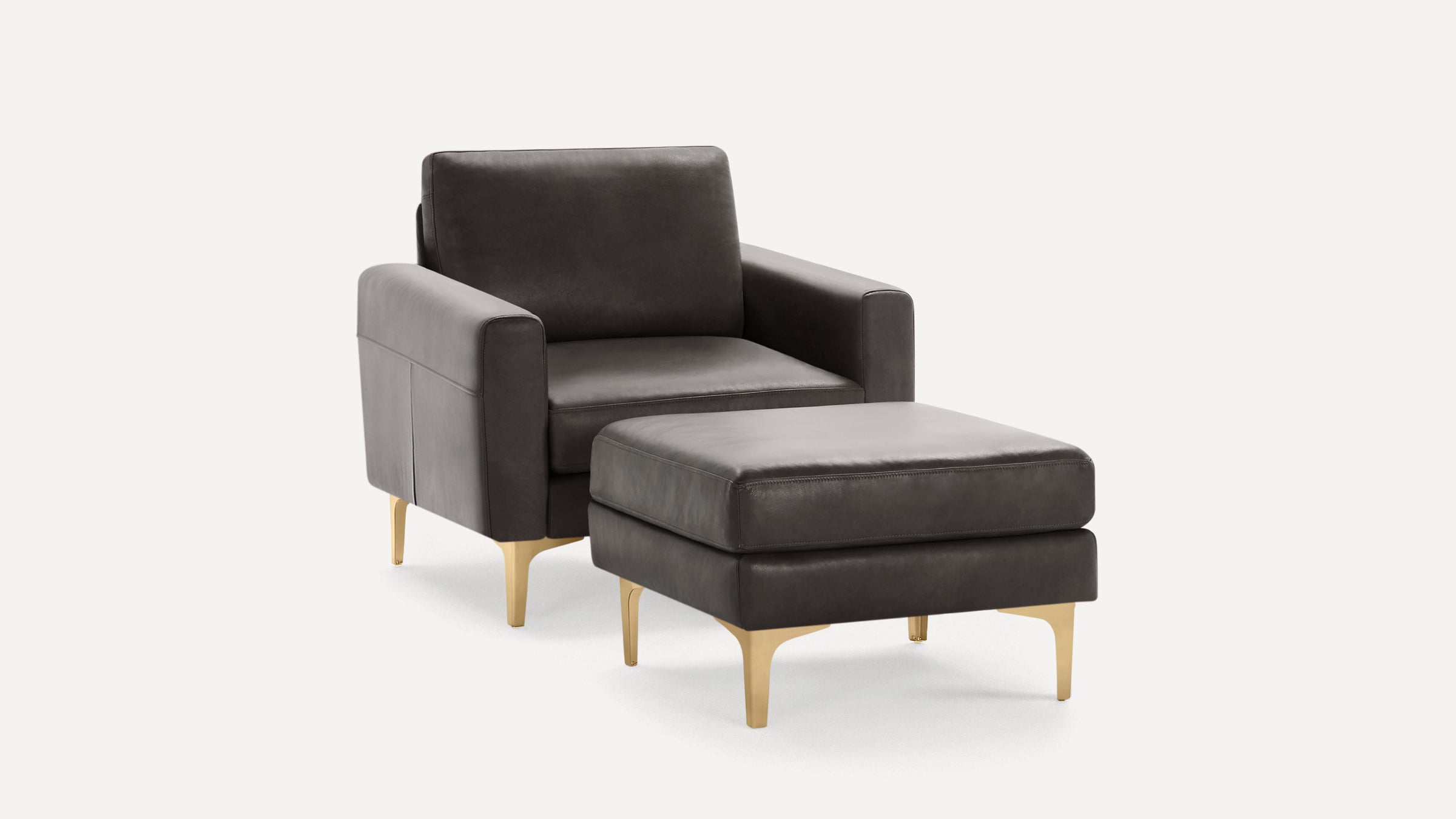Dark gray leather armchair with matching ottoman, featuring sleek gold metal legs and modern, minimalist design.