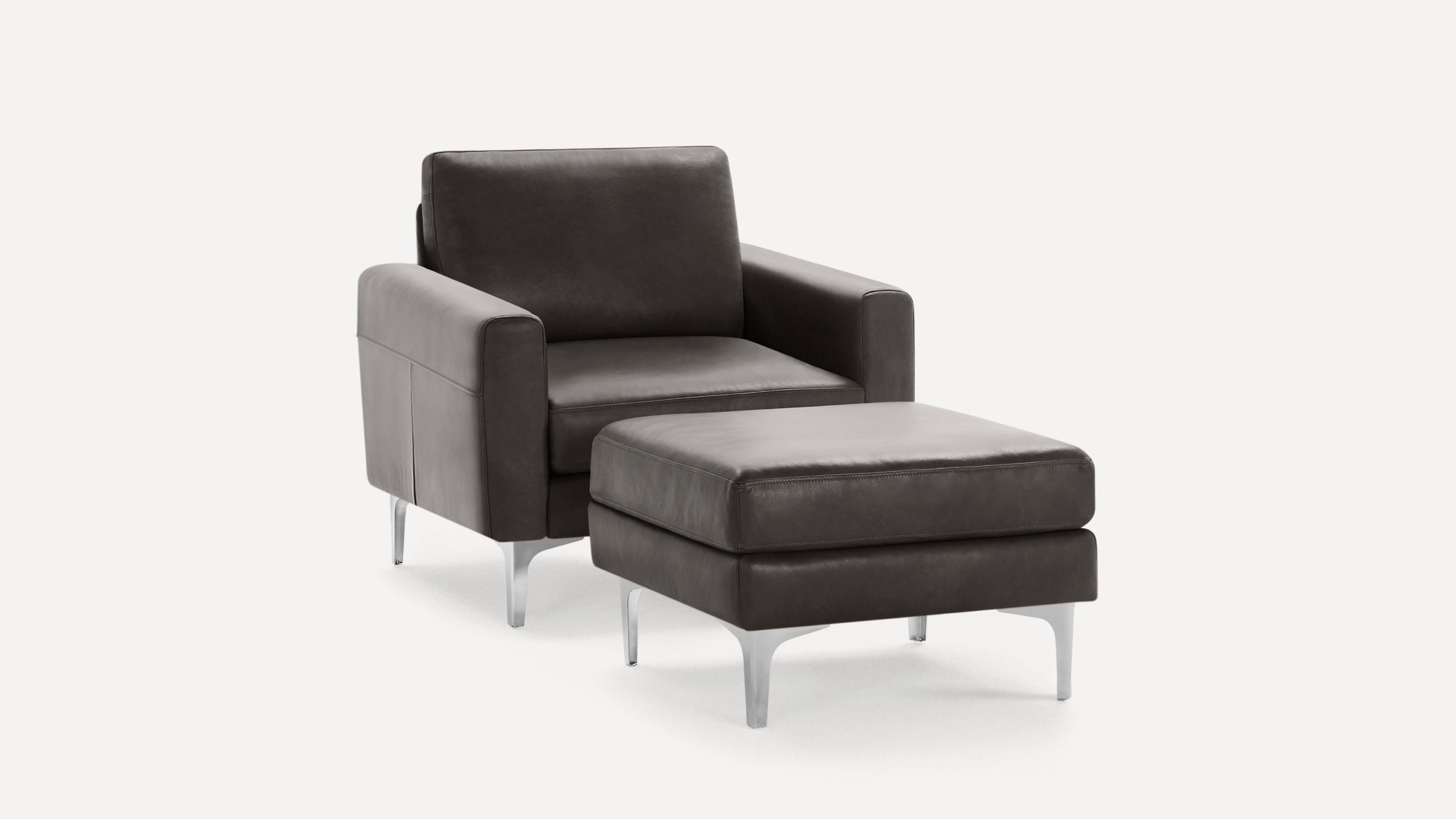 Dark gray leather armchair with matching ottoman, both featuring sleek metal legs and modern, minimalist design.