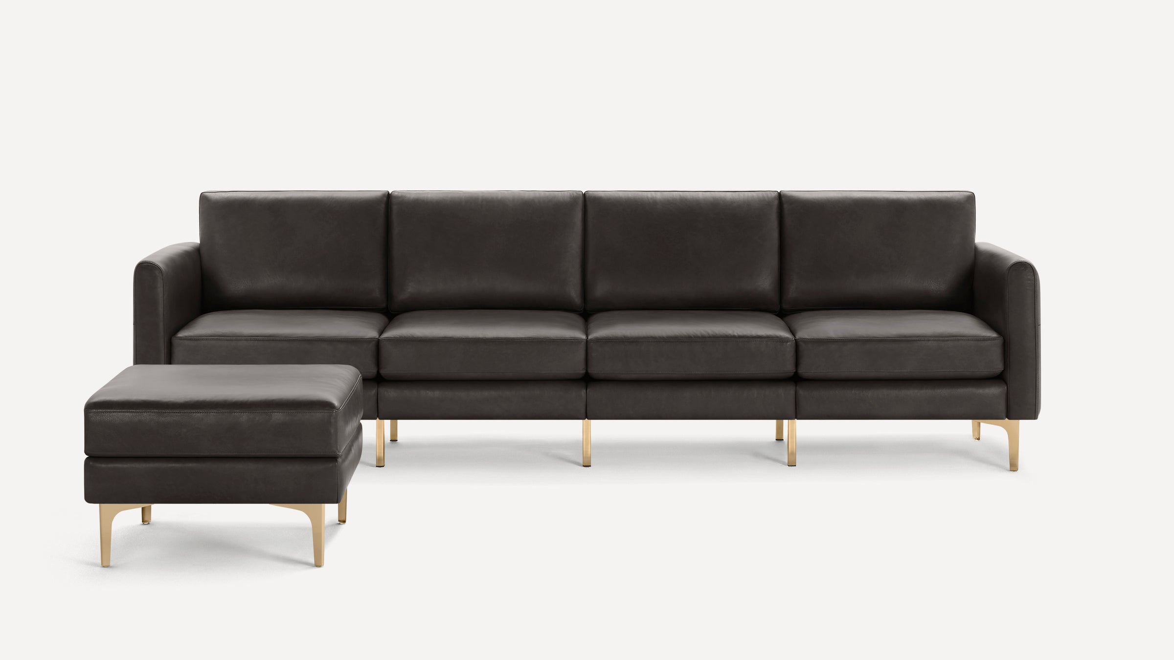 Modern dark gray leather sectional sofa with clean lines and slim gold metal legs, featuring a matching ottoman on the left side.