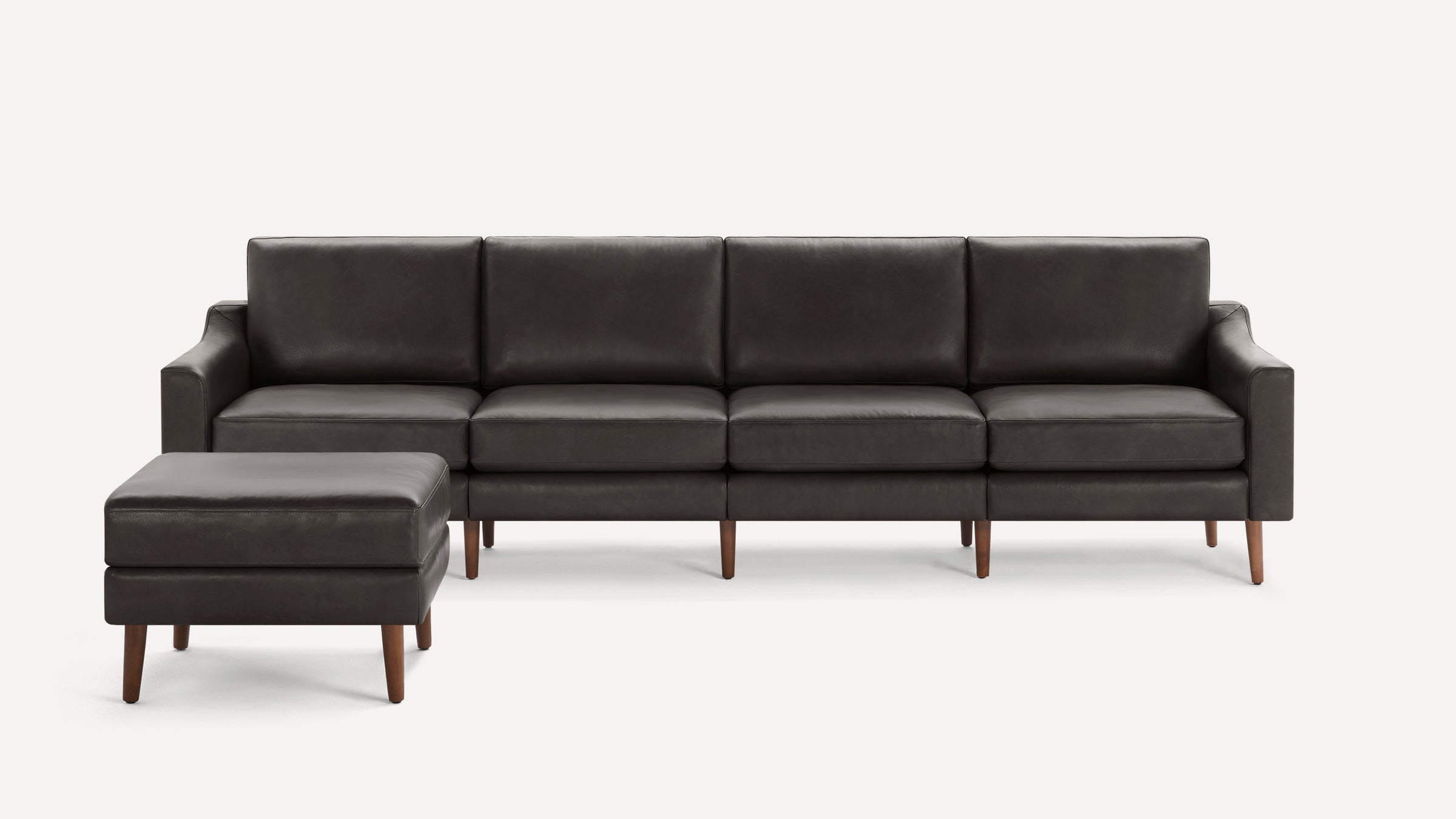 Dark gray leather sectional sofa with a matching ottoman, mid-century modern design, wooden legs, and clean lines.