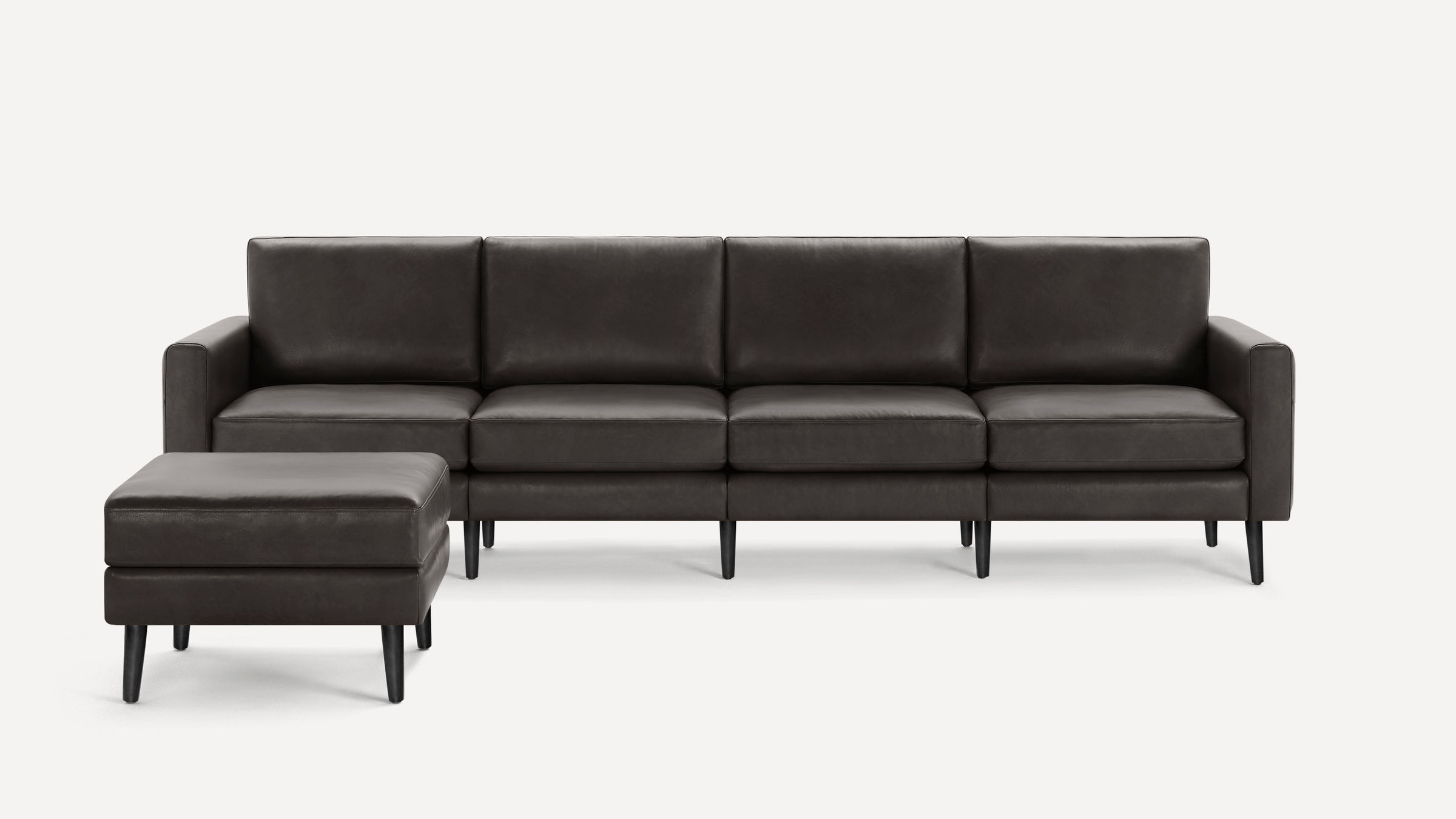 Modern dark gray leather sectional sofa with clean lines, four seats, and a matching ottoman on black legs.