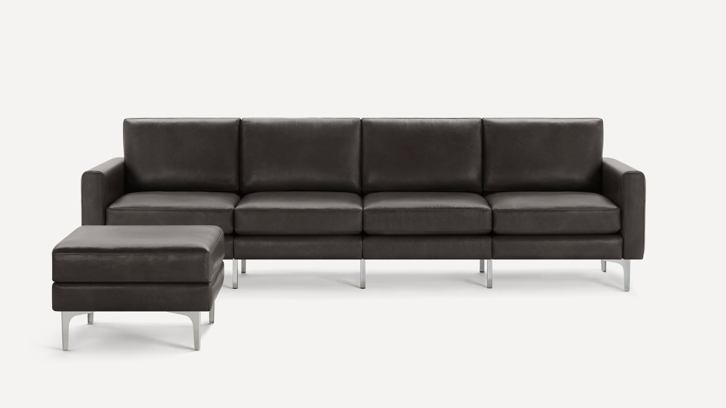Modern dark gray leather sectional sofa with metal legs and matching ottoman on left side, minimalist design.