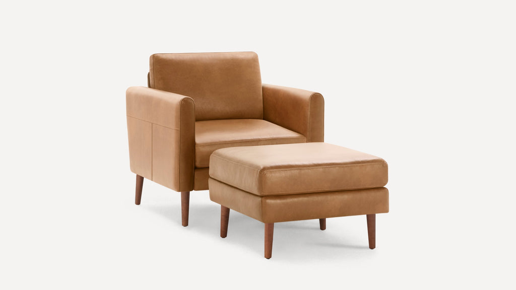 Modern tan leather armchair with matching ottoman, wooden legs, clean lines, and minimalist design on white background.