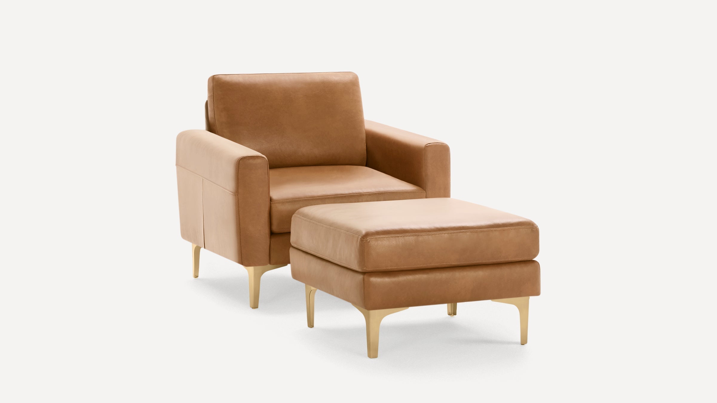 Tan leather armchair with matching ottoman, featuring gold-toned legs and modern, clean-lined design on a white background.