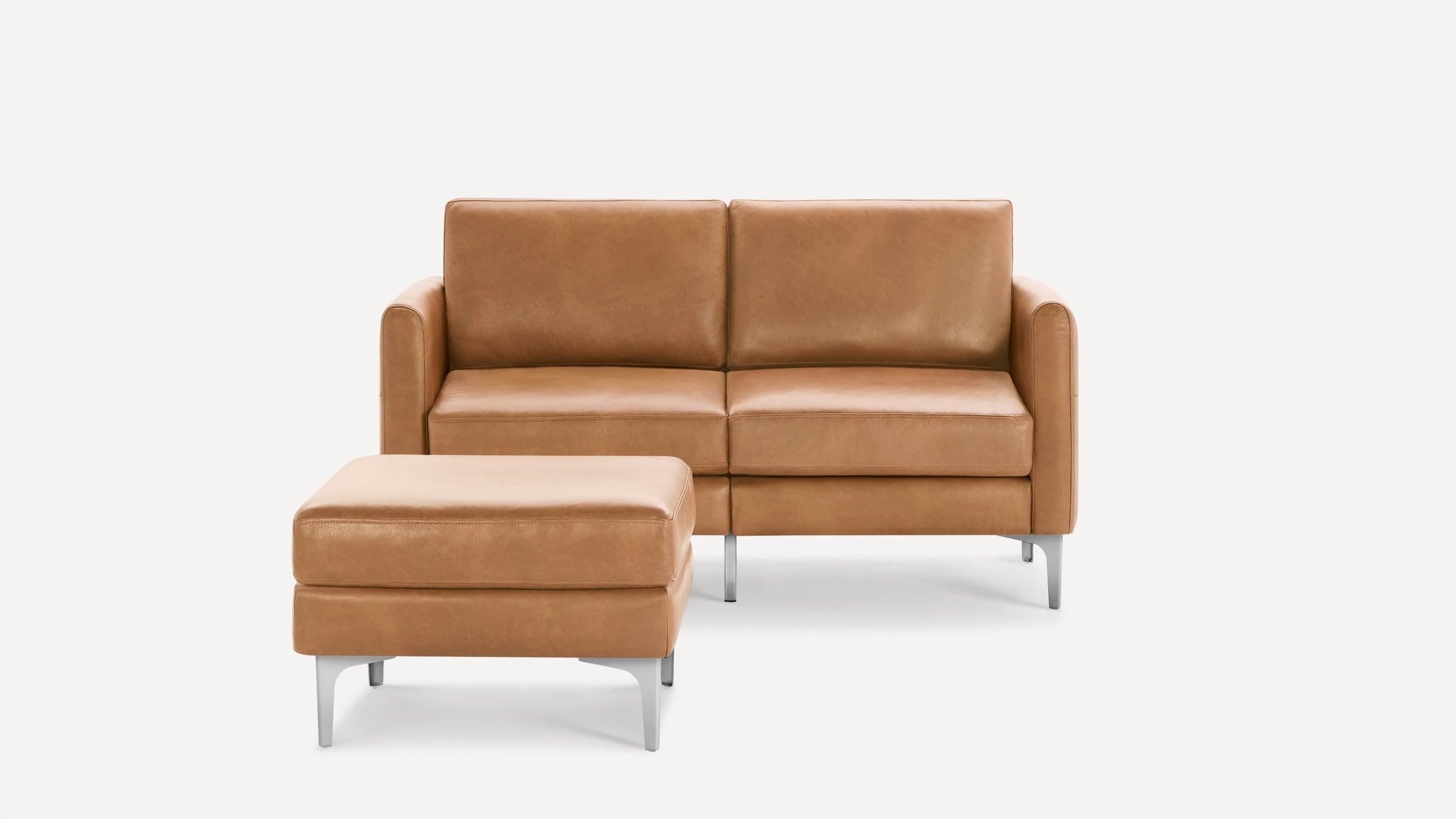 Modern two-seater tan leather sofa with matching ottoman, featuring clean lines and metal legs on a white background.