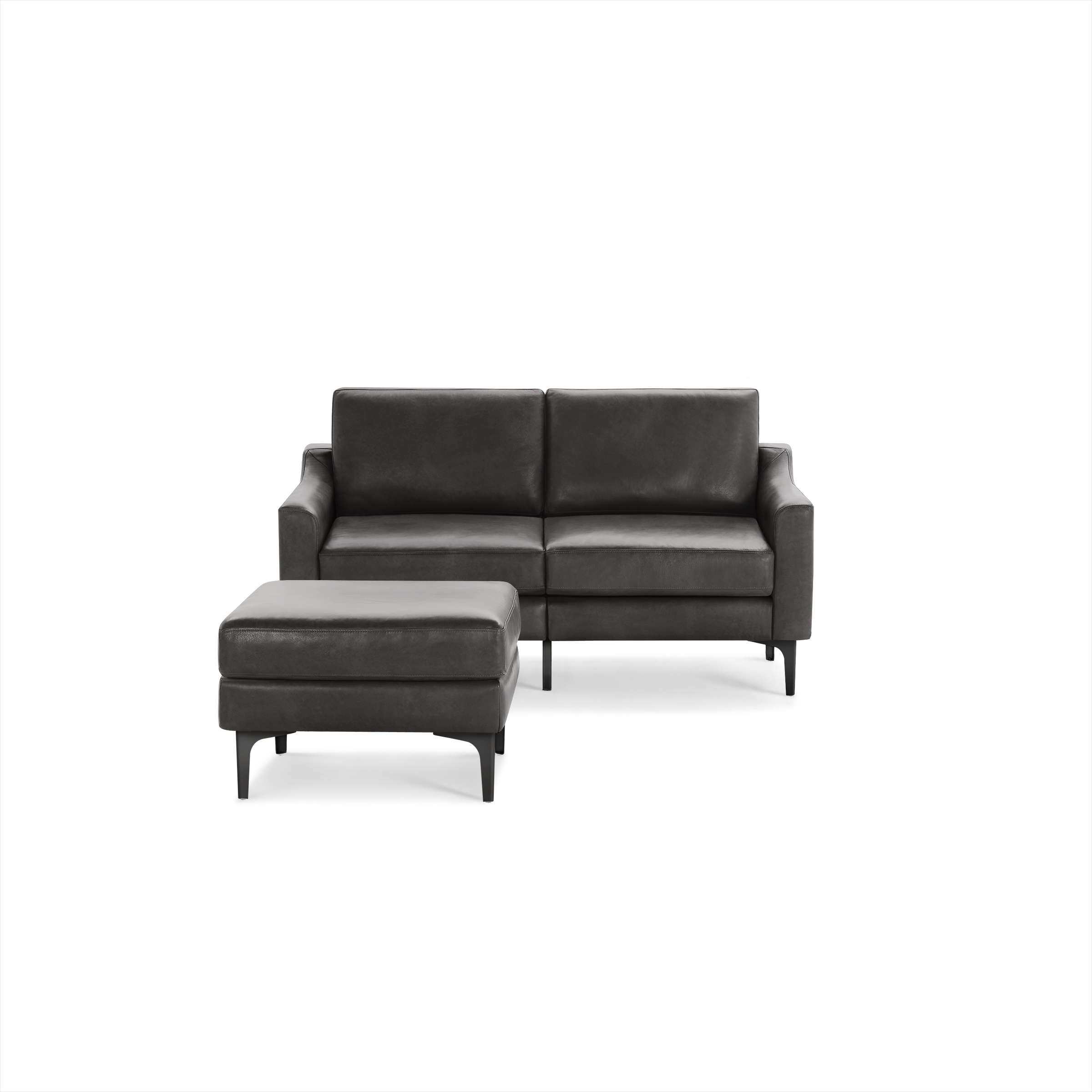 Modern dark gray leather loveseat with matching ottoman, featuring clean lines and slim black metal legs.
