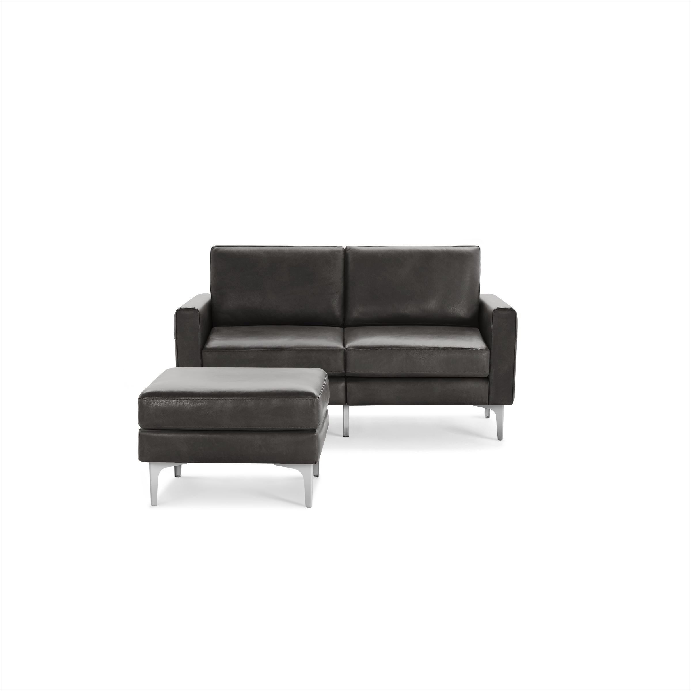 Modern dark gray leather loveseat with clean lines and a matching ottoman, featuring sleek metal legs.