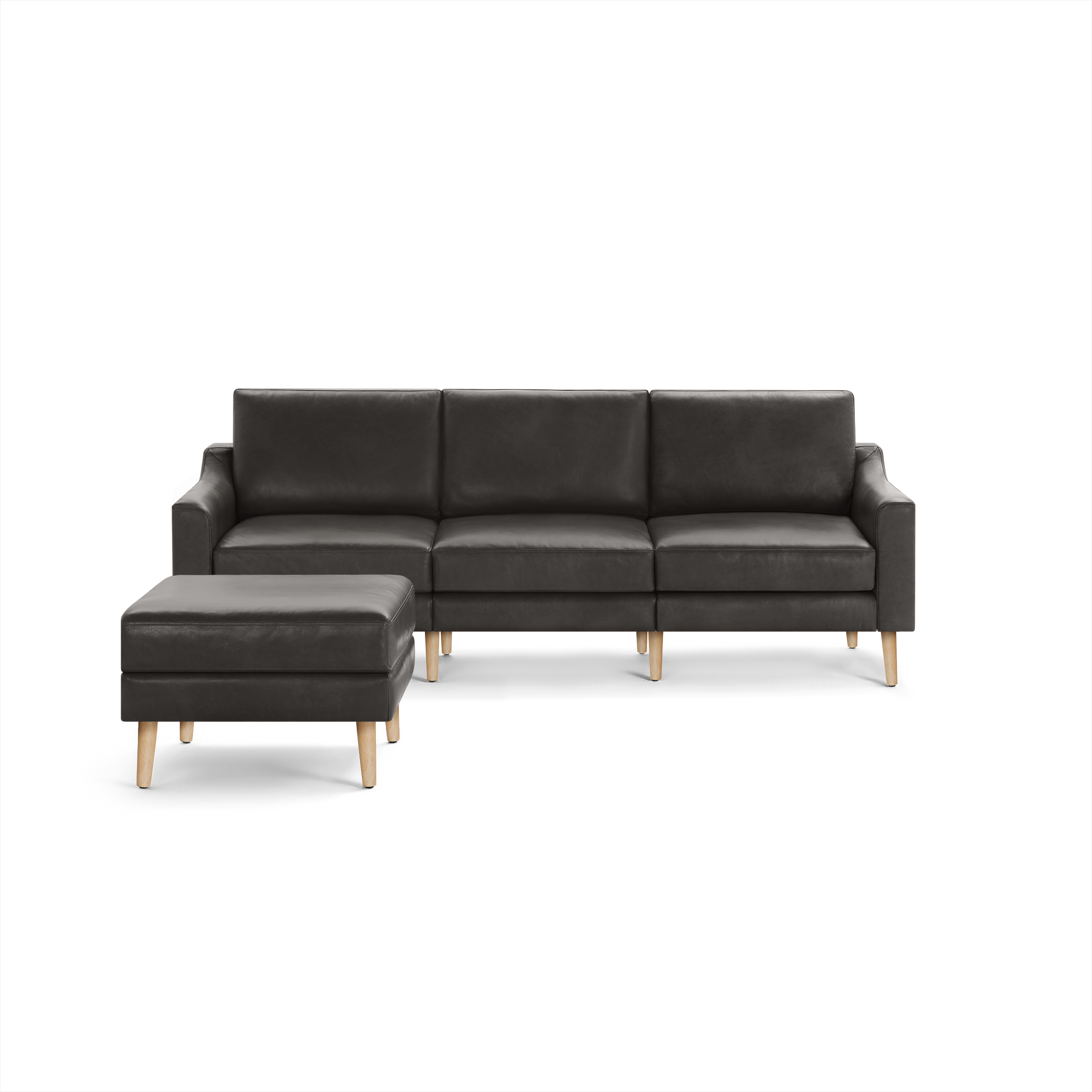 Modern dark gray leather sectional sofa with three cushions and a matching ottoman, both featuring light wooden legs.