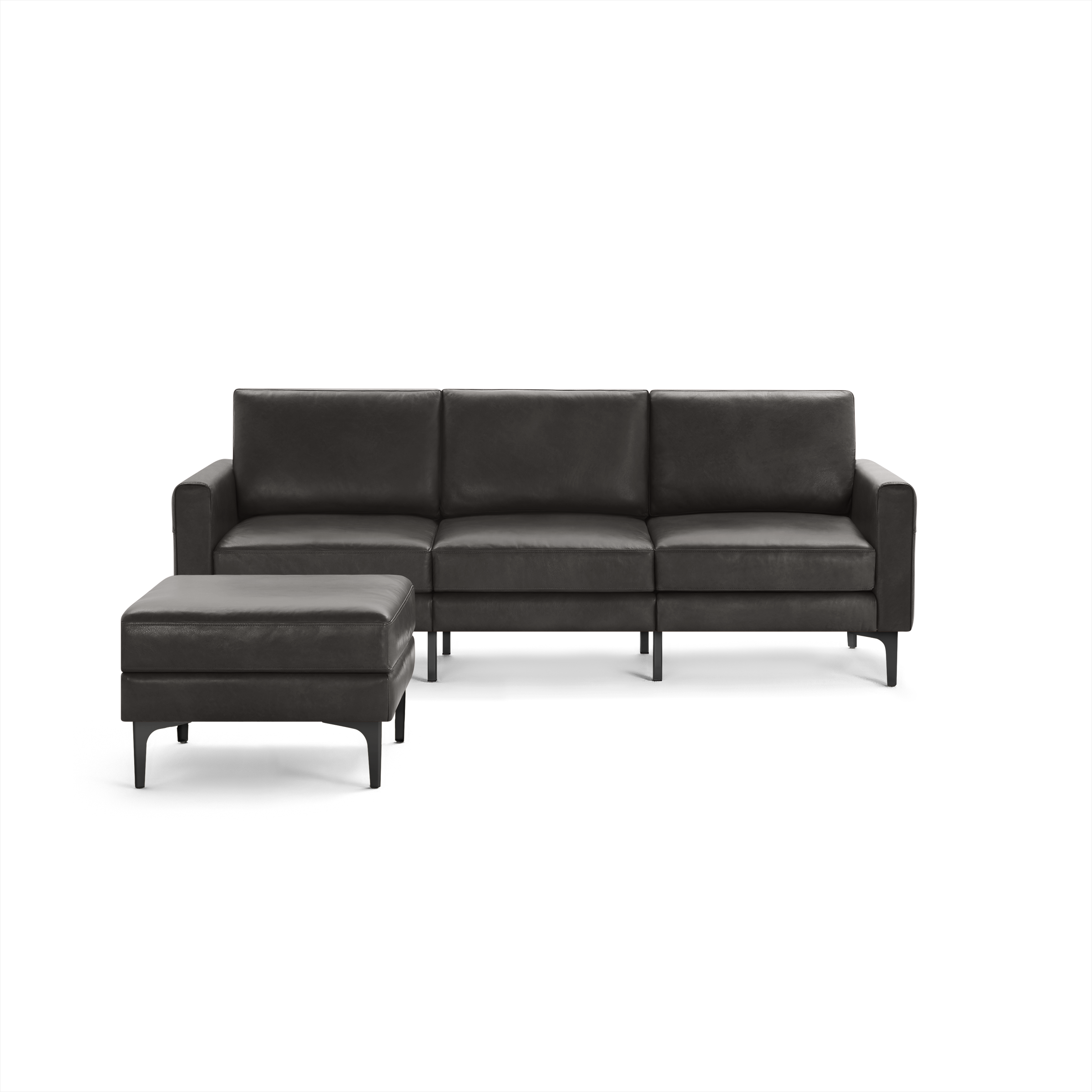 Dark grey modern three-seater leather sofa with square armrests and matching ottoman, both featuring black slender legs.