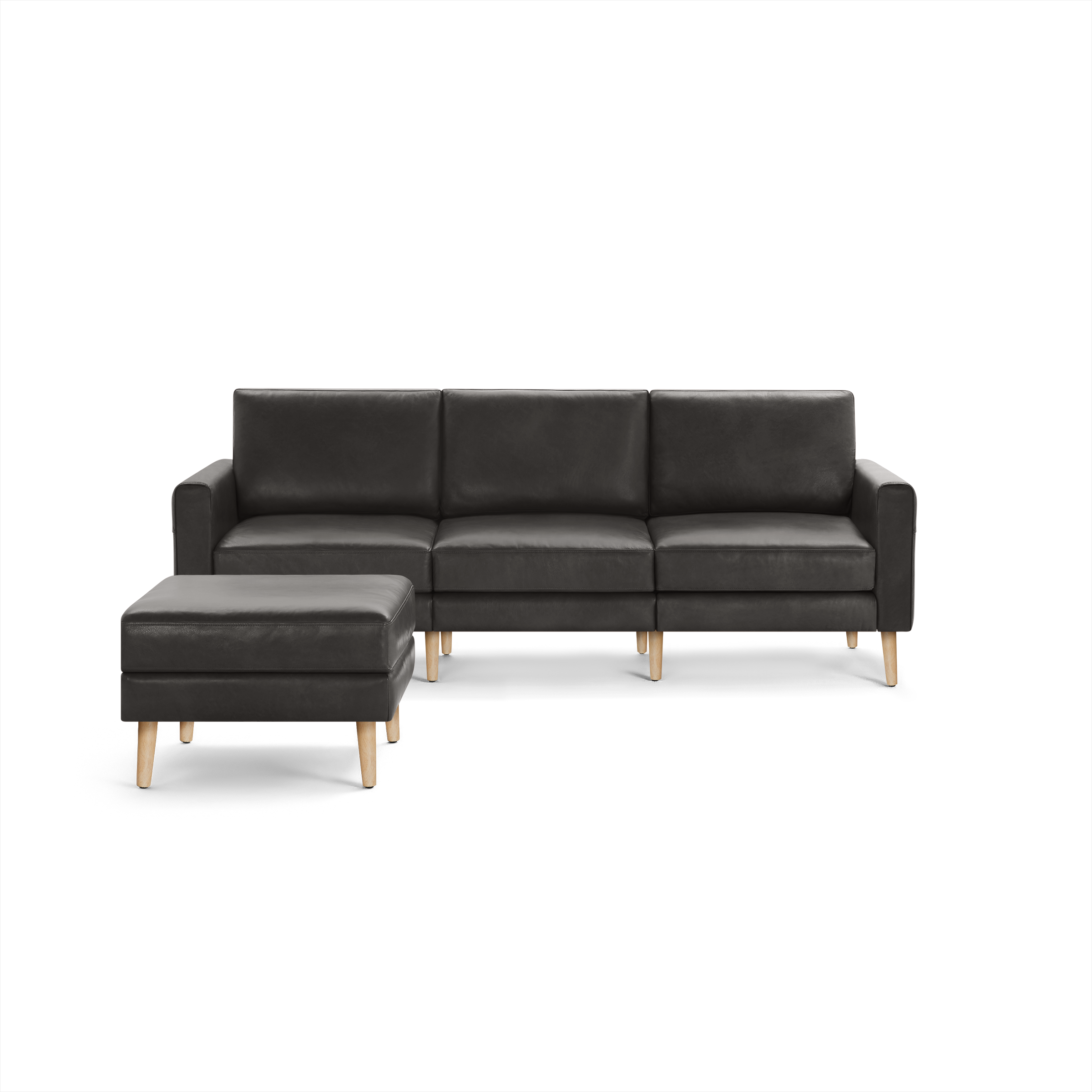 Dark gray leather sectional sofa with three seat cushions and matching ottoman, both supported by light wooden legs.