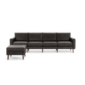 Modern dark gray leather sectional sofa with wooden legs and matching ottoman on the left side, sleek and minimalist design.