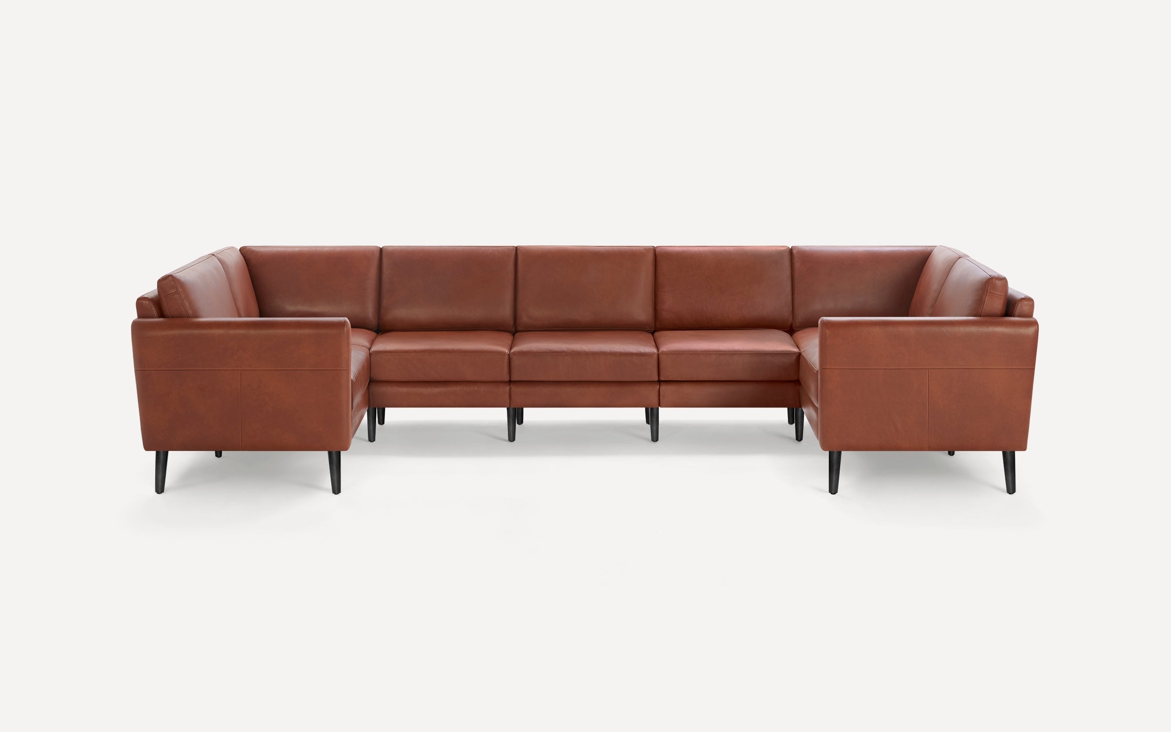 U-shaped sectional sofa upholstered in warm brown leather with clean lines and black tapered legs on a white background.