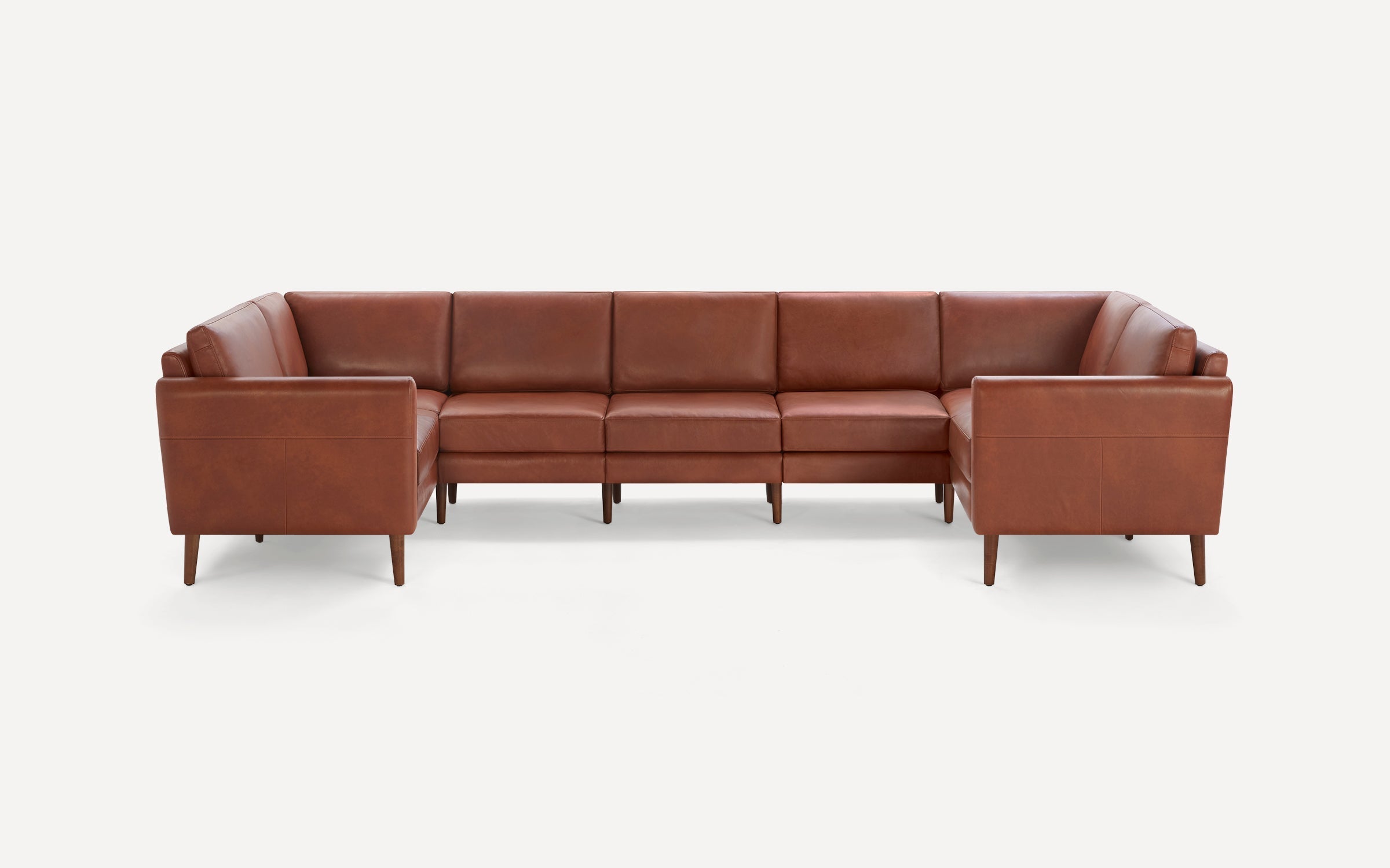 Brown leather U-shaped sectional sofa with clean lines and tapered wooden legs on a white background.