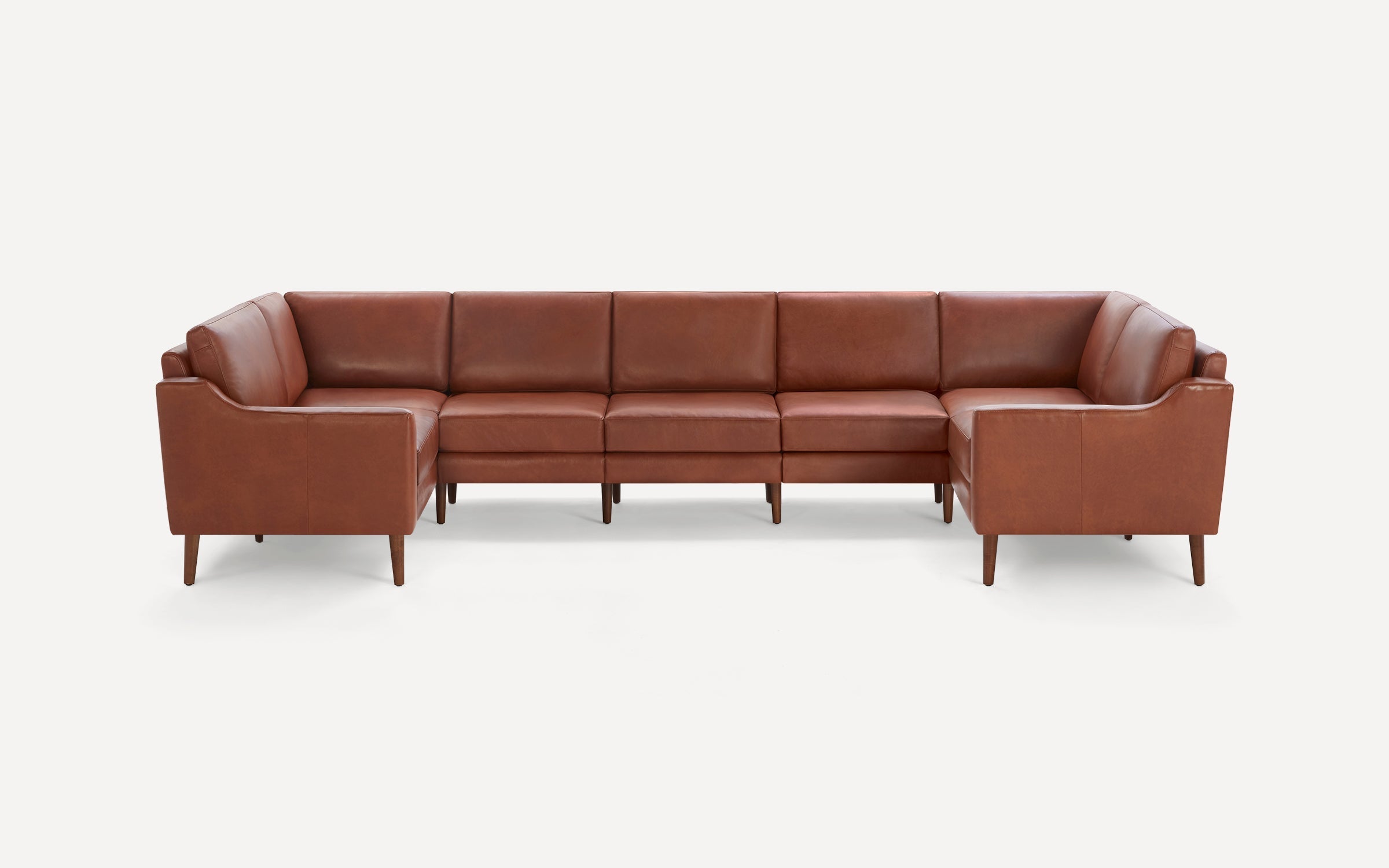 Large L-shaped sectional sofa with mid-century modern design, brown leather upholstery, and wooden tapered legs.