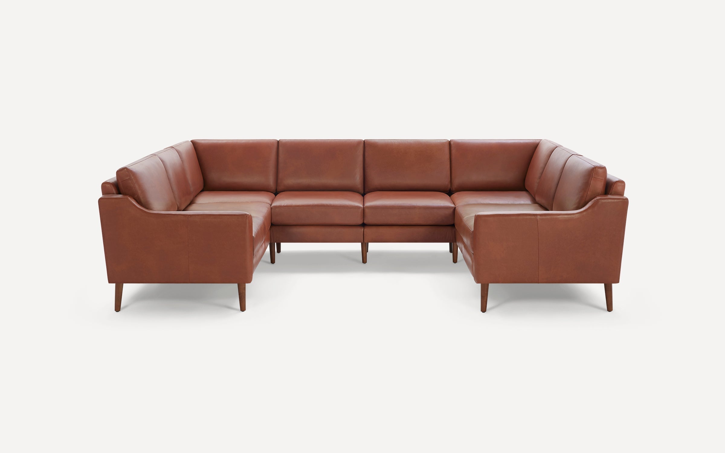 Brown leather U-shaped sectional sofa with wooden legs, featuring cushioned seats and backs, modern and minimalistic design.