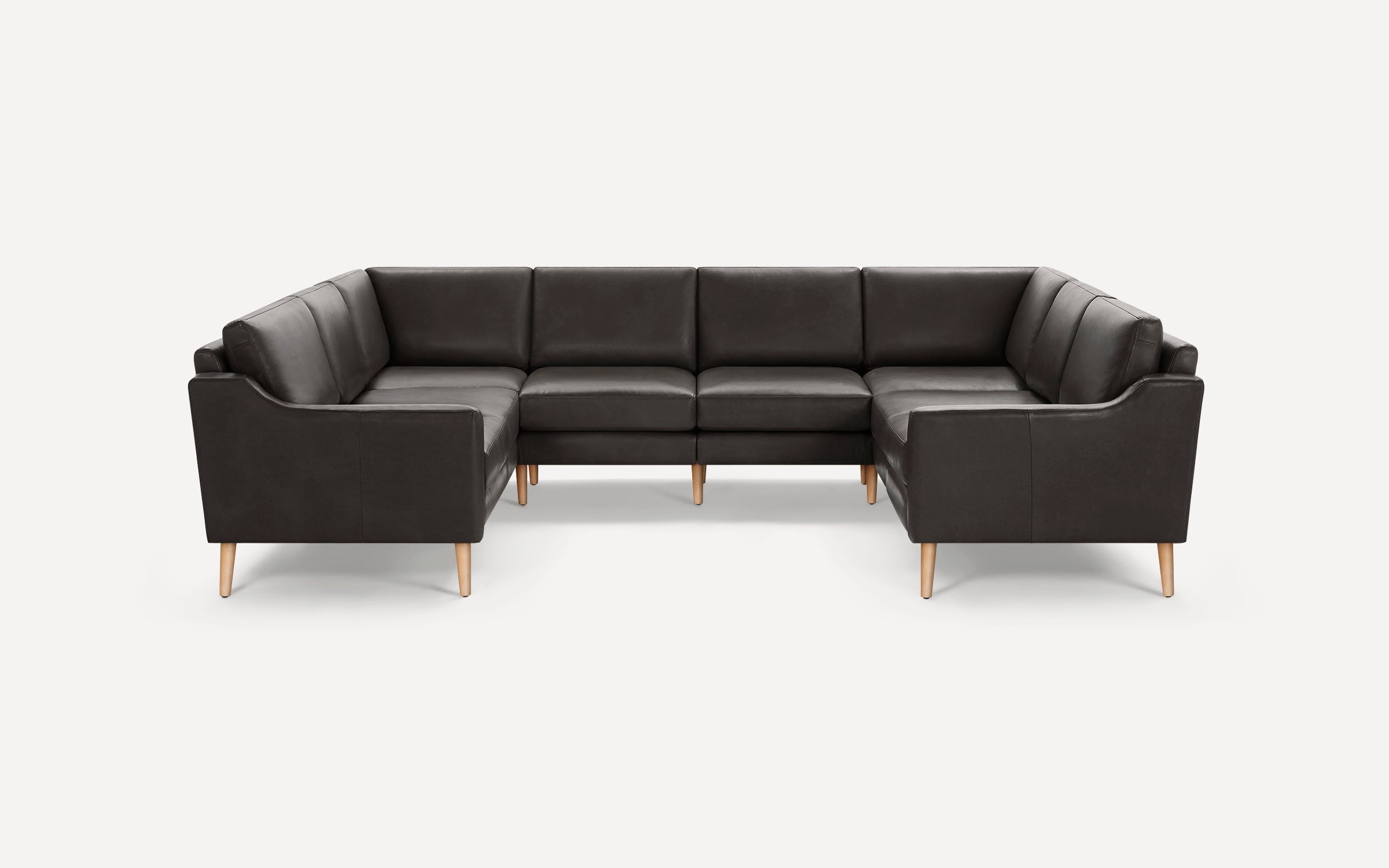Dark gray leather U-shaped sectional sofa with wooden legs, modern design, padded seats and backrests, clean lines, set against a plain white background.