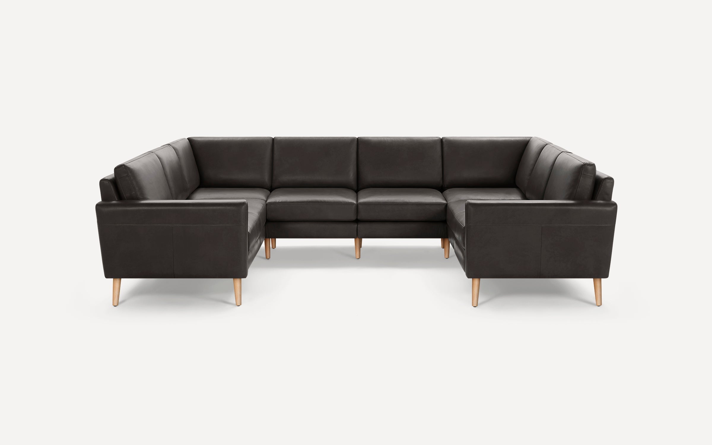 Modern U-shaped dark gray leather sectional sofa with wooden tapered legs, clean lines, and cushioned backrest on light background.