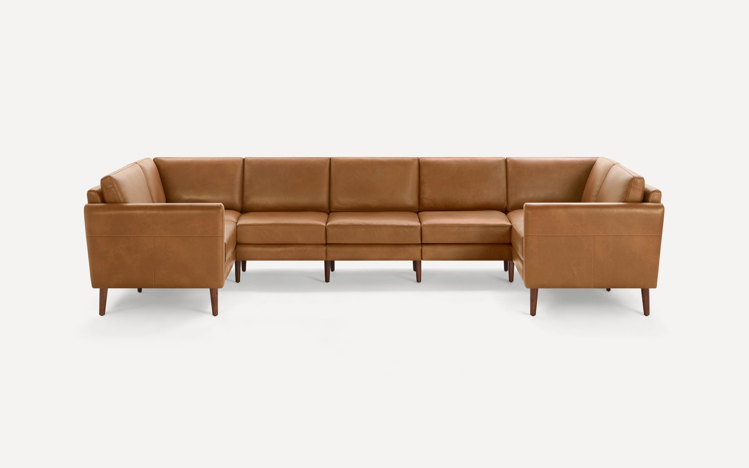 Modern L-shaped sectional sofa with tan leather upholstery, cushioned seats, and sleek wooden legs on a white background.