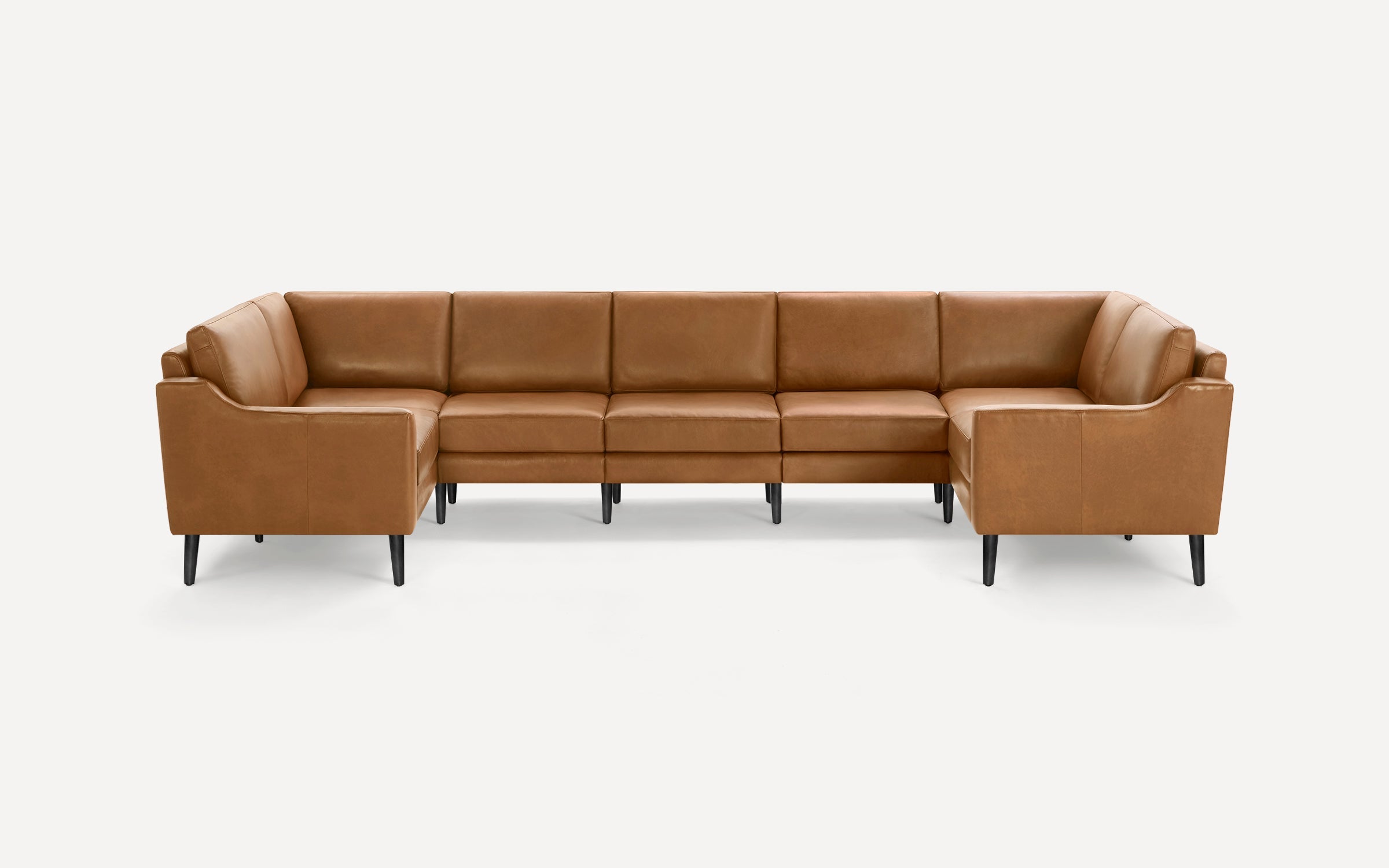 Large L-shaped sectional sofa in tan leather with clean lines and black tapered legs, designed for modern living spaces.