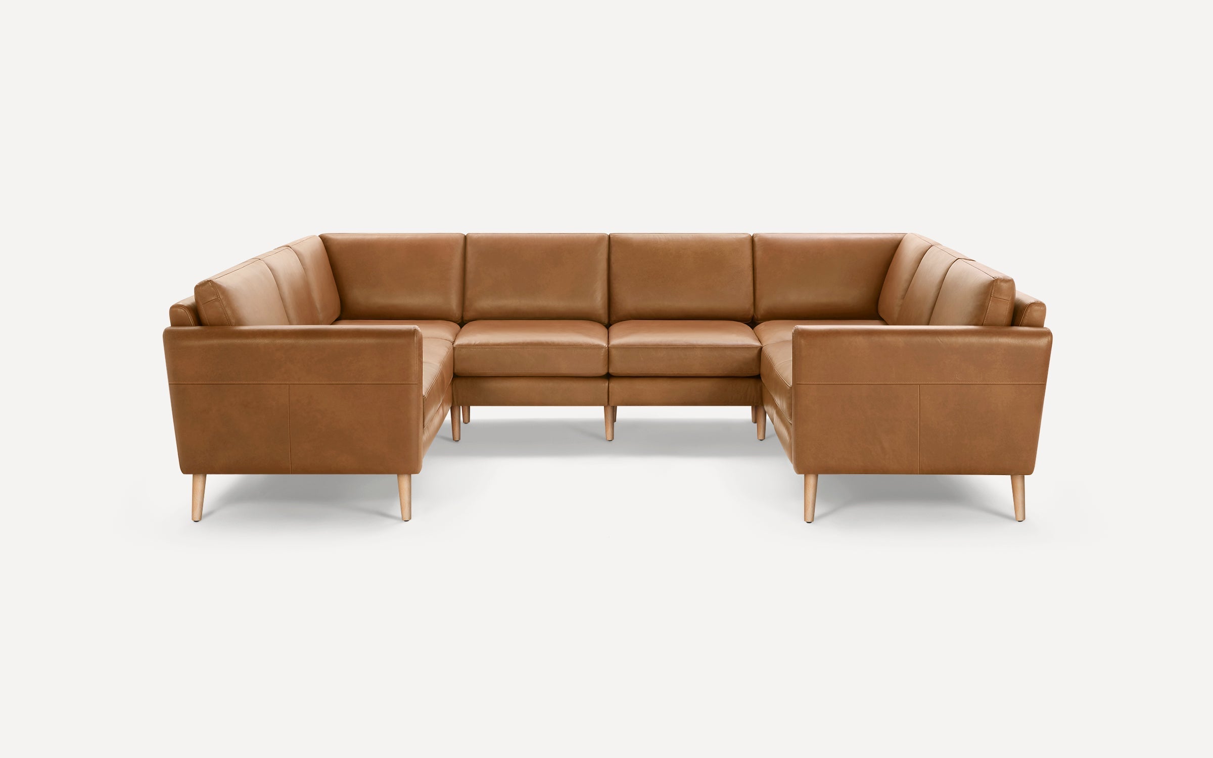 Modern U-shaped sectional sofa with tan leather upholstery and light wooden legs on a white background.
