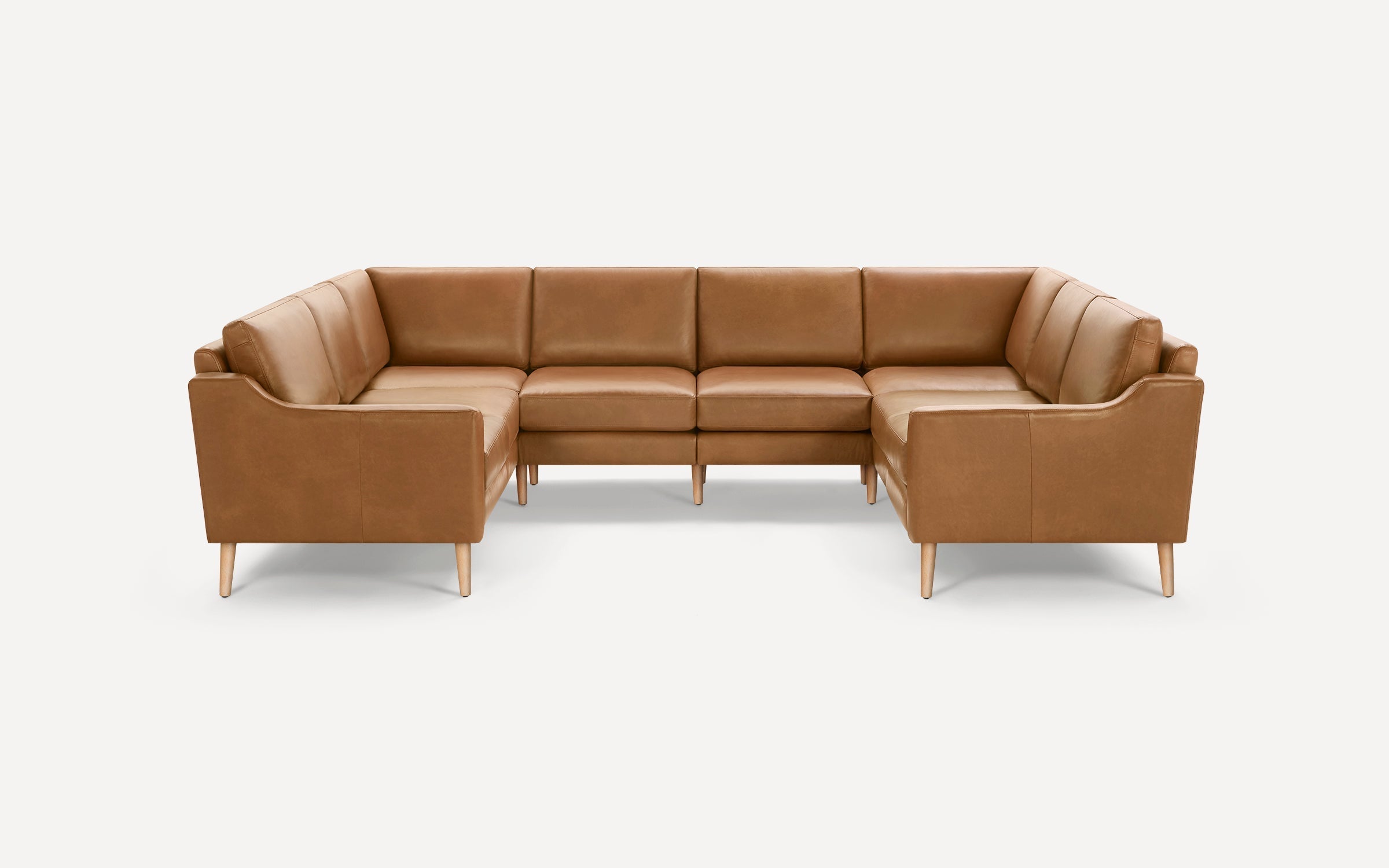 Modern U-shaped sectional sofa featuring light brown leather upholstery and wooden tapered legs.