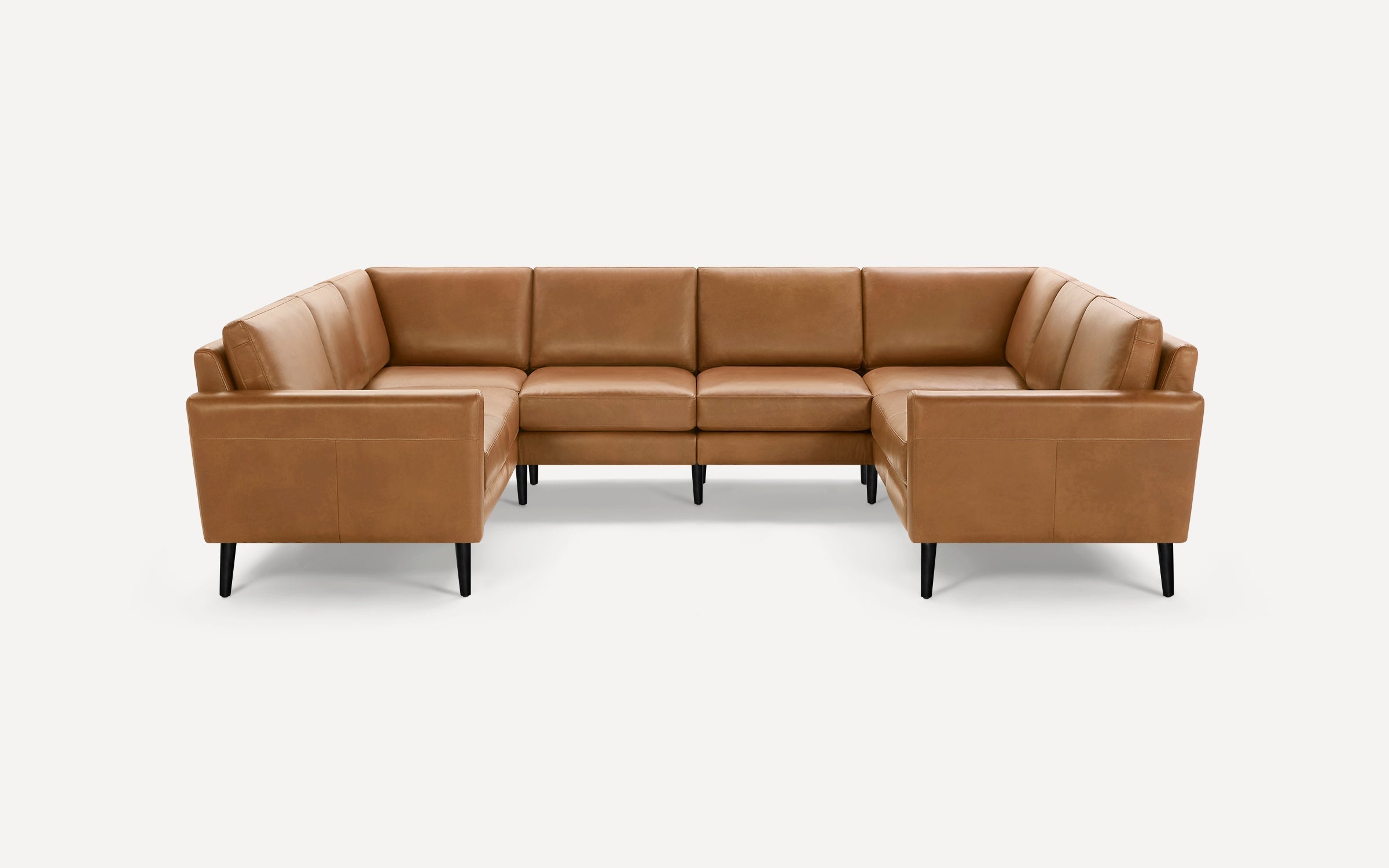 Modern U-shaped sectional sofa upholstered in smooth tan leather with black tapered wooden legs.