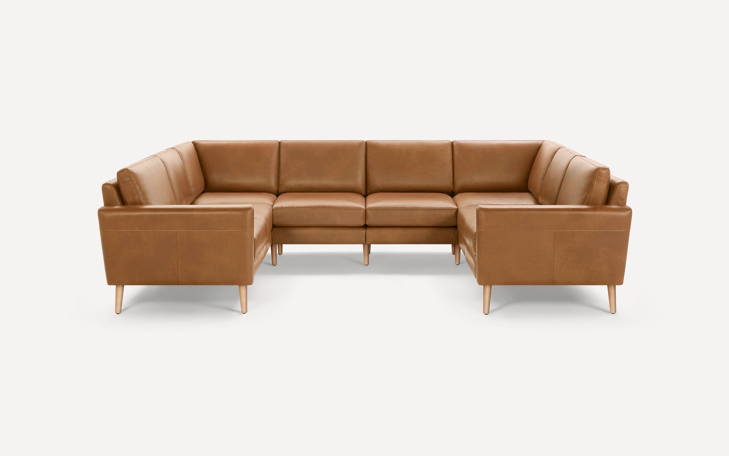 Large L-shaped sectional sofa in light brown leather with wooden legs, featuring clean lines and modern design.
