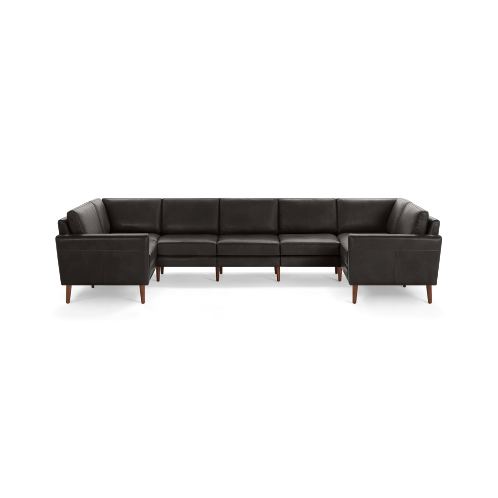 Large sectional sofa with dark gray leather upholstery and wooden legs, featuring a modern, boxy design with cushioned seats and backrests.