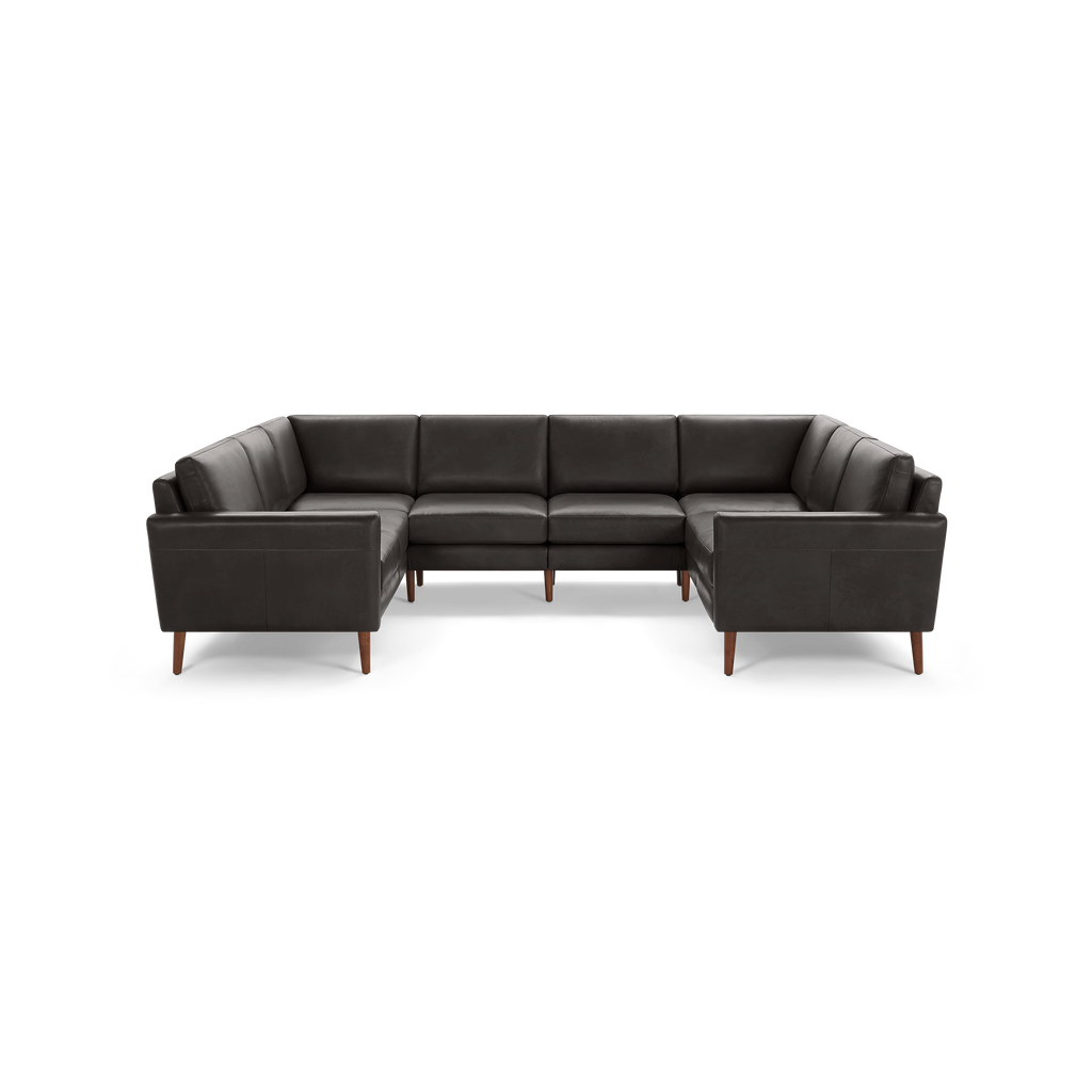 Large dark gray leather U-shaped sectional sofa with clean lines and wooden tapered legs on a black background.