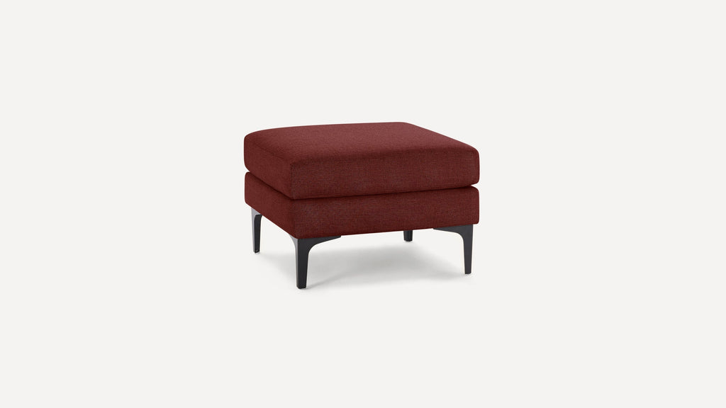 Square ottoman with dark red fabric upholstery and black tapered legs on a plain white background.